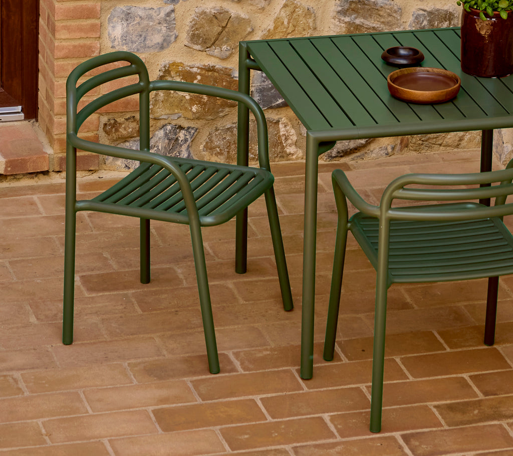 Sillón Green Bliss al lado de una mesa a juego, con un diseño minimalista y una estética relajada, colocado sobre una superficie texturizada.