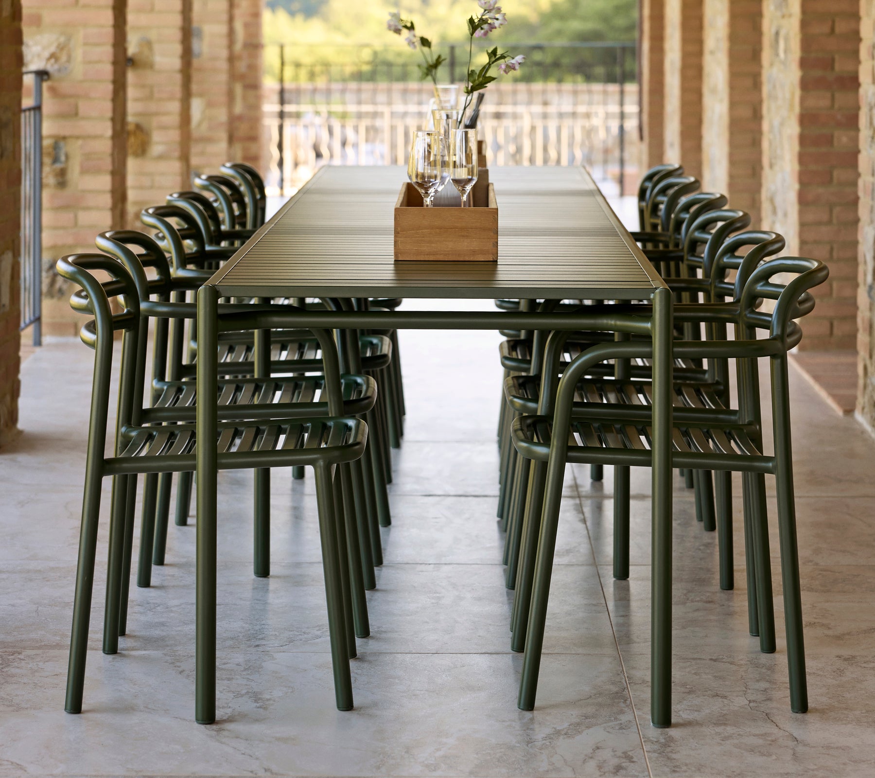 Una larga mesa decorada con sillas Bliss de color verde oscuro con reposabrazos, complementada por un centro decorativo.