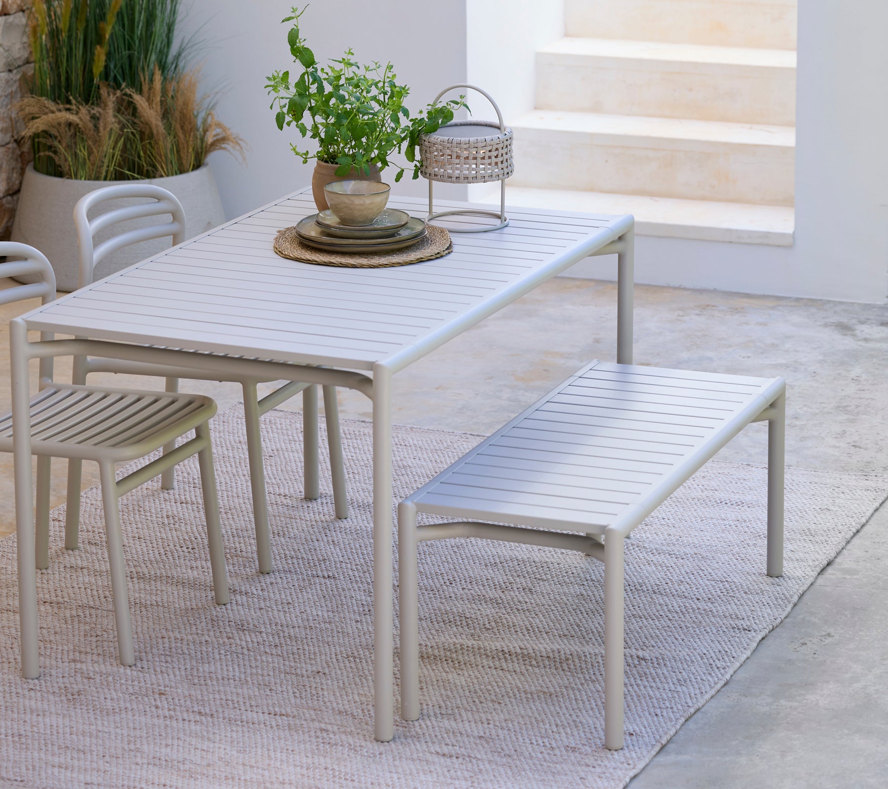 Mesa de comedor blanca moderna con banco y silla a juego en un entorno minimalista.