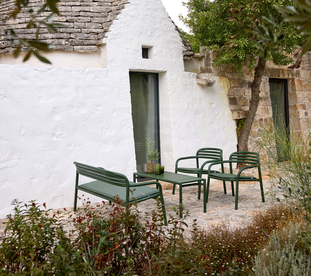 Sofá y sillones exteriores verdes con una mesa de café en un ambiente acogedor.