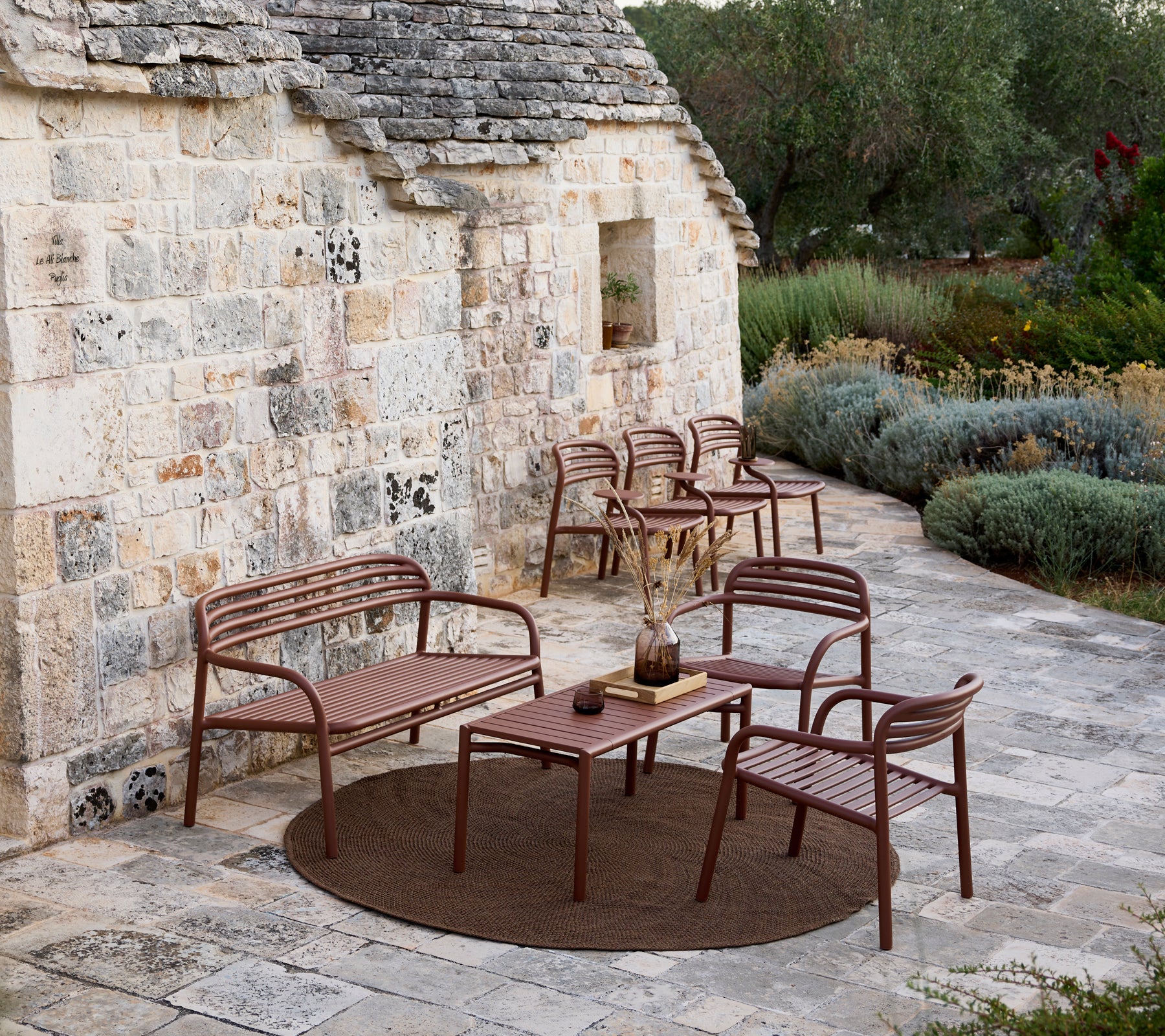 Sofá exterior marrón, sillas y juego de mesa en un área de salón moderna.