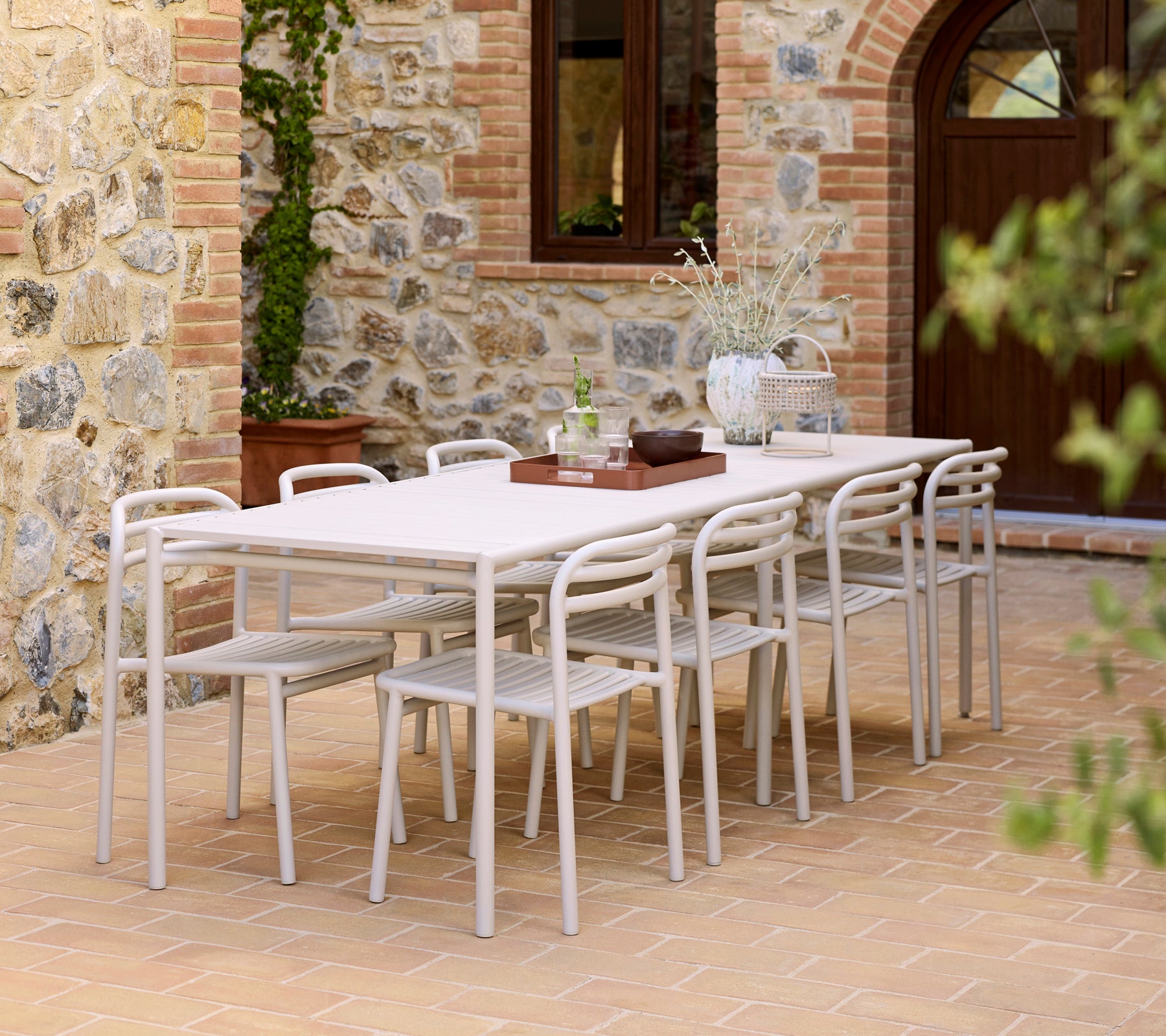 Una configuración de comedor moderna con una mesa Bliss, sillas Bliss y una bandeja Club sobre una superficie texturizada.