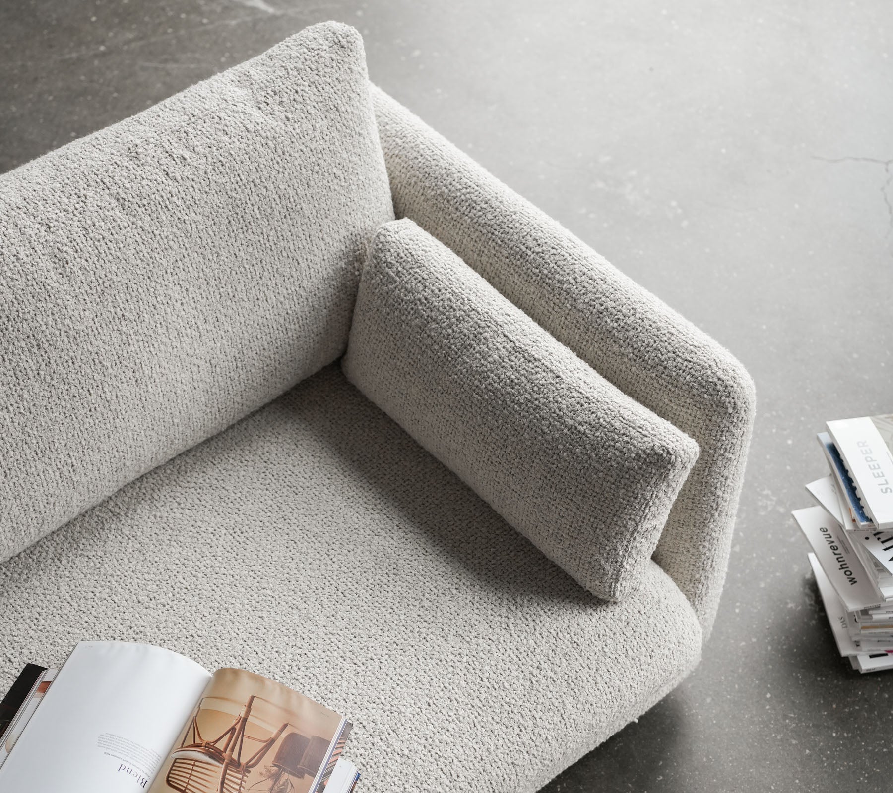 Sofá elegante con una superficie texturizada, que cuenta con un reposabrazos mullido y un cojín cómodo, perfecto para relajarse y leer.