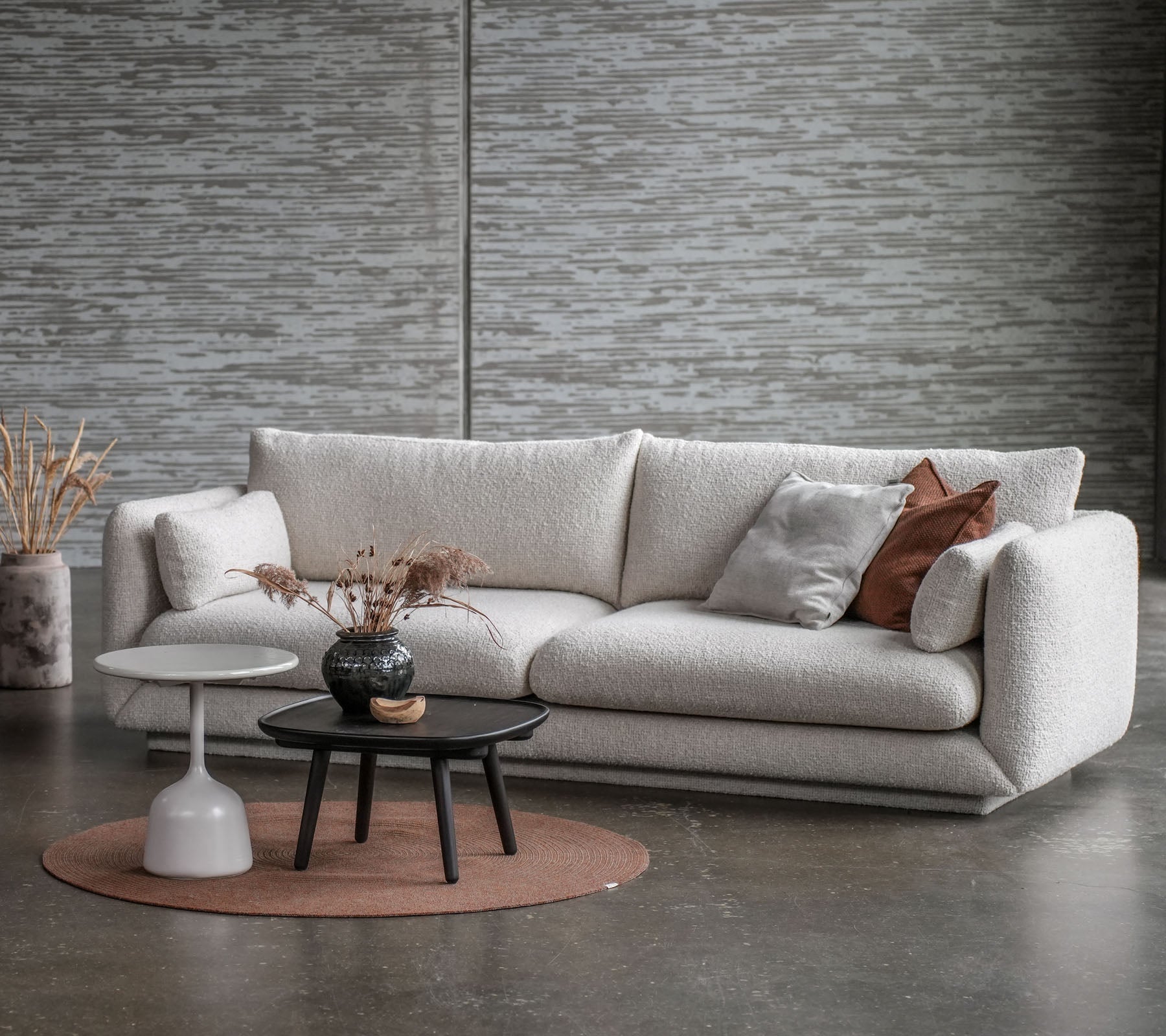 Una zona de estar elegante con un sofá de tonos claros, una mesa de café redonda y elementos decorativos en colores suaves.