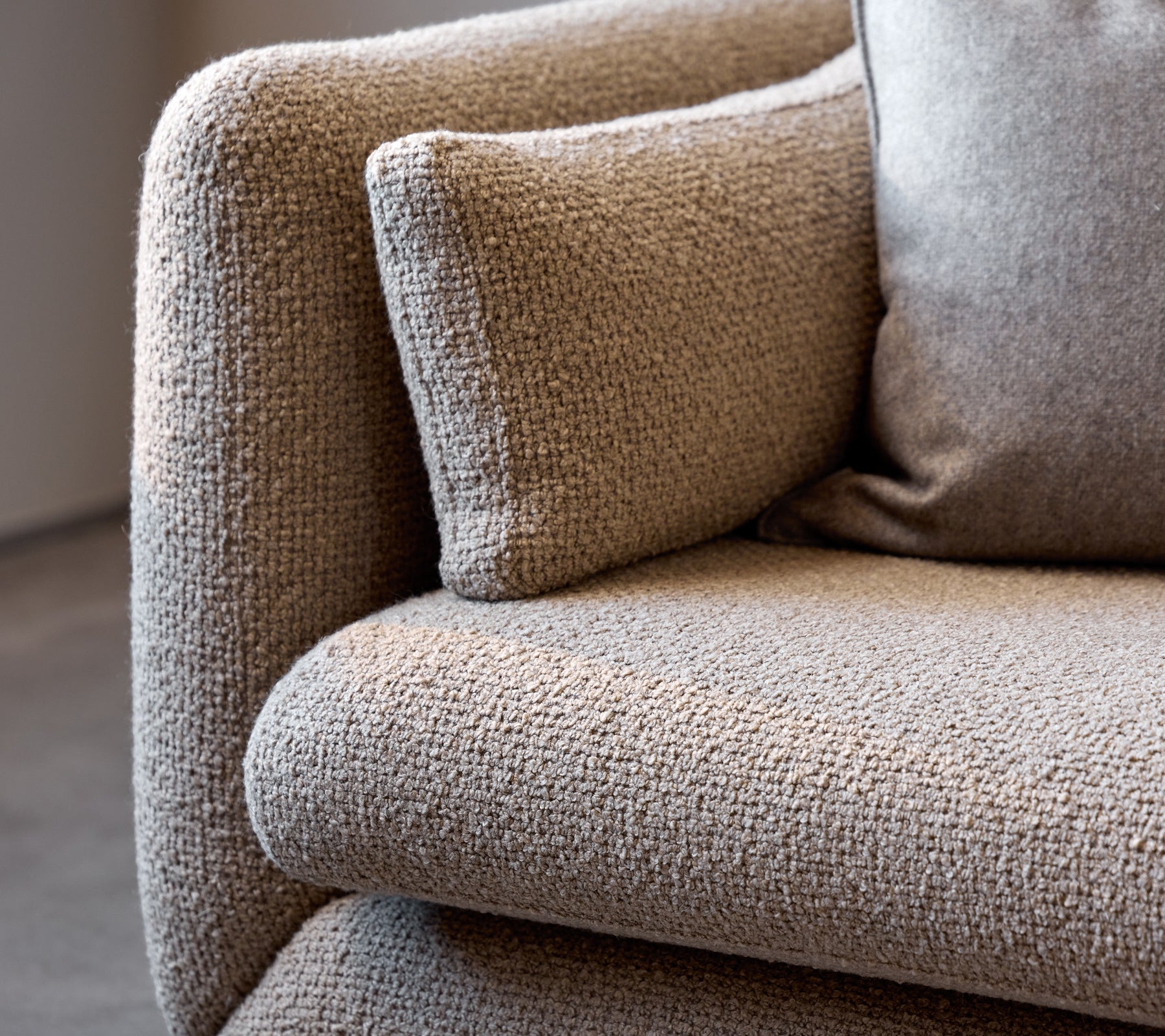 Primer plano de un reposabrazos de sofá Bloom taupe, que muestra su tela texturizada y su suave cojín para mayor comodidad.