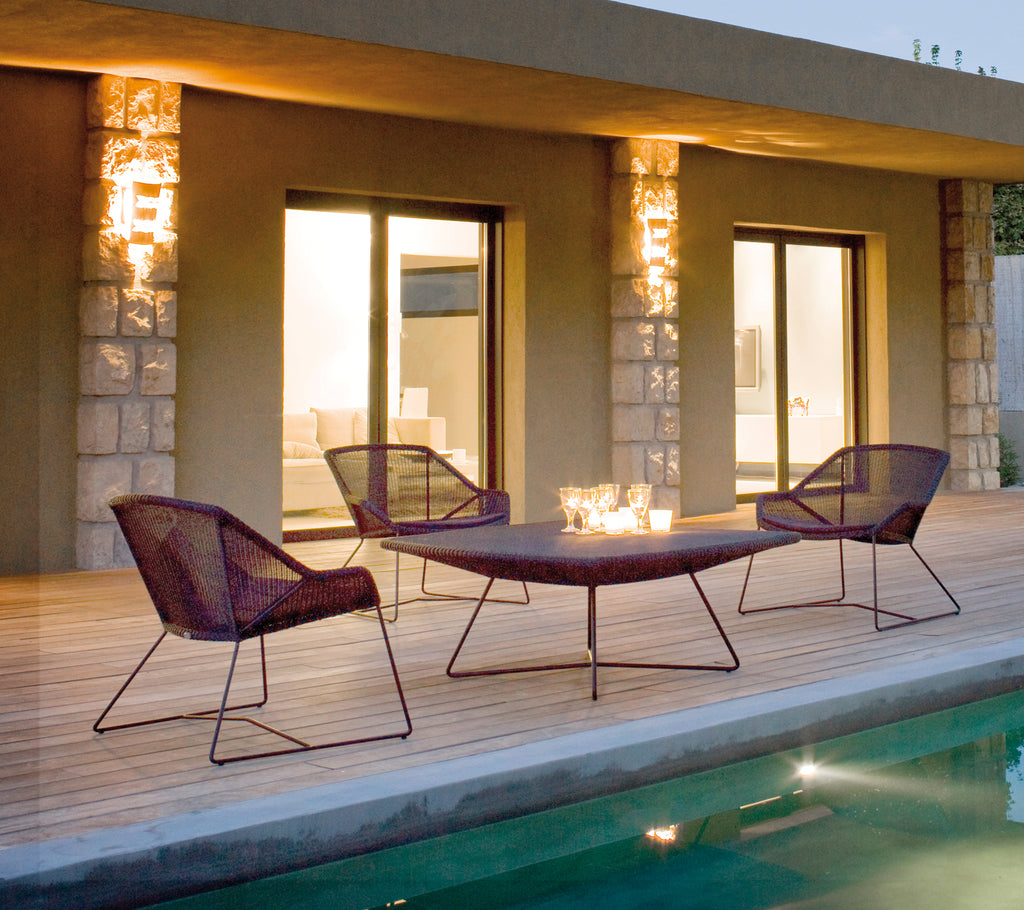 Configuración moderna al aire libre con sillas de lounge moradas y una mesa a juego cerca de una piscina.