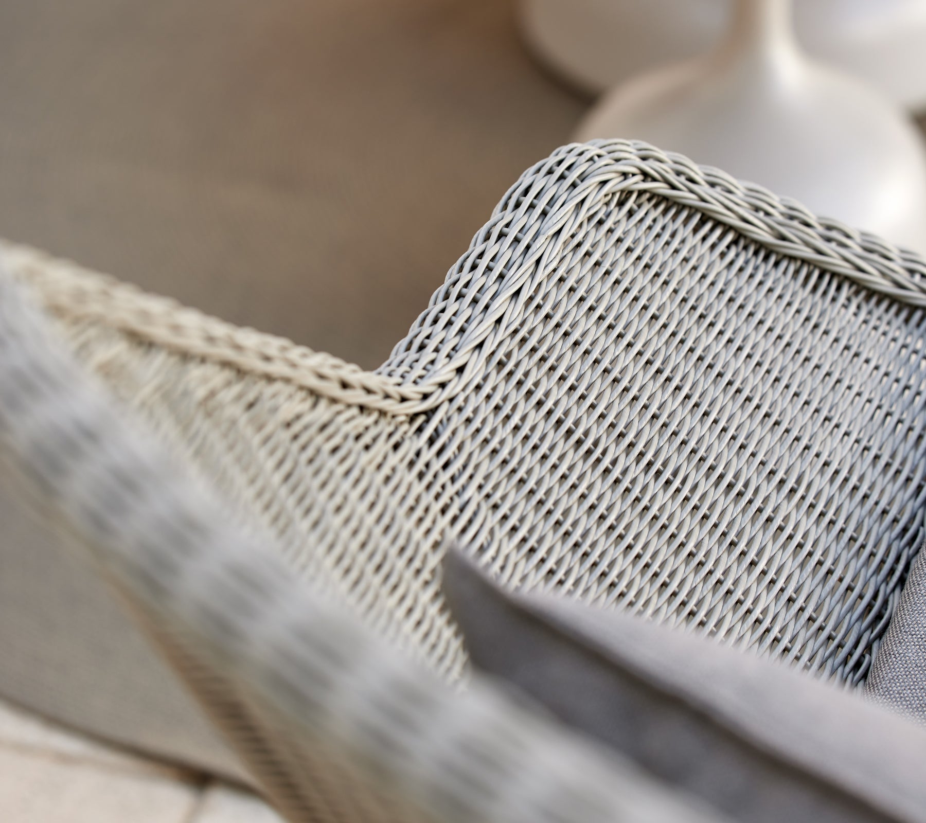 Sillón de mimbre gris con un cojín gris.