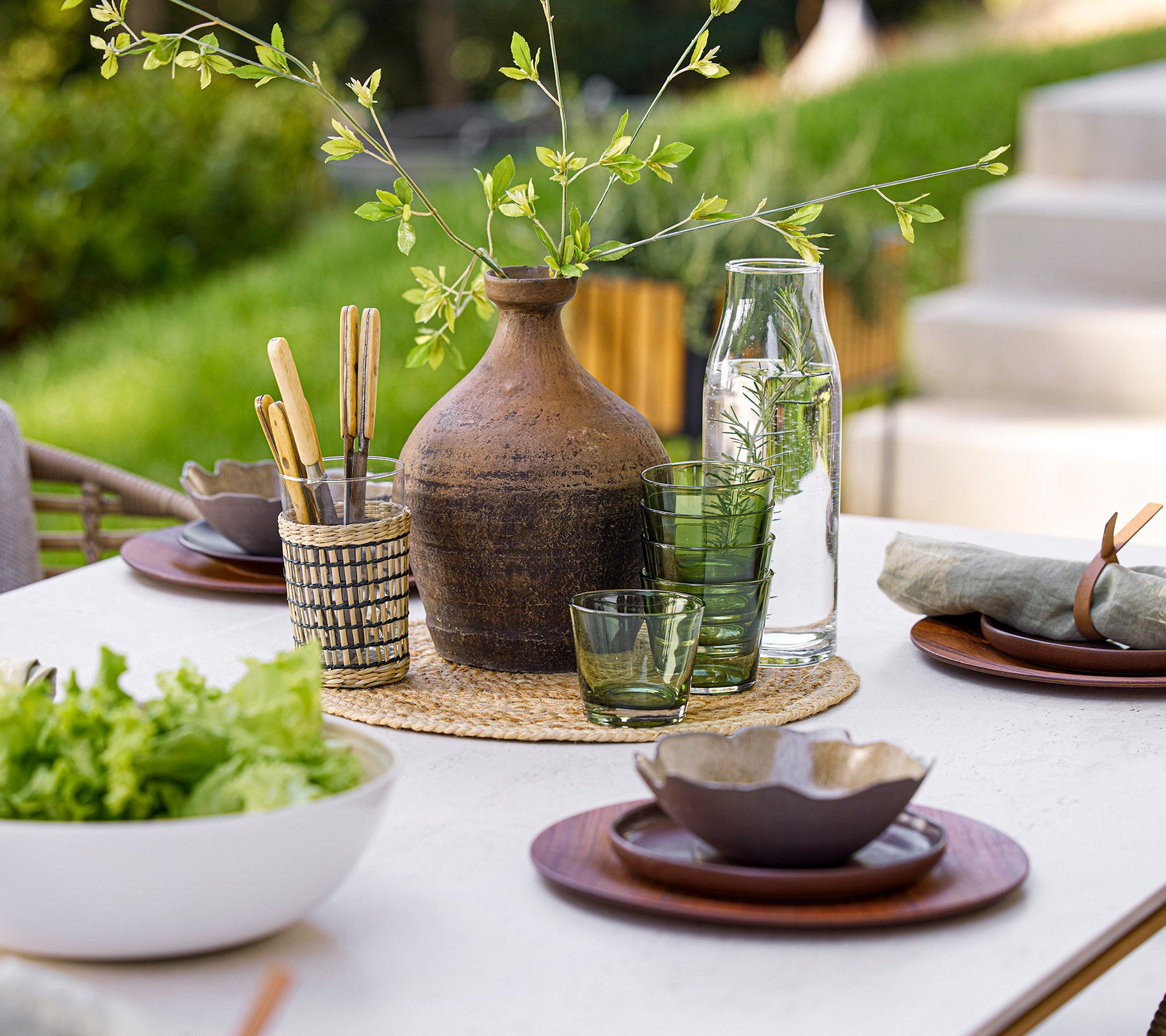 Una mesa de comedor bellamente dispuesta con cristalería, elementos naturales y elegante vajilla, creando una atmósfera de comedor serena.