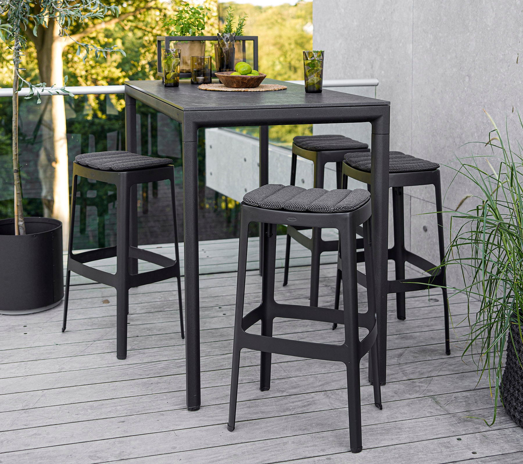Una mesa moderna con cuatro taburetes a juego, con un diseño elegante y una estética minimalista, frente a un entorno natural.