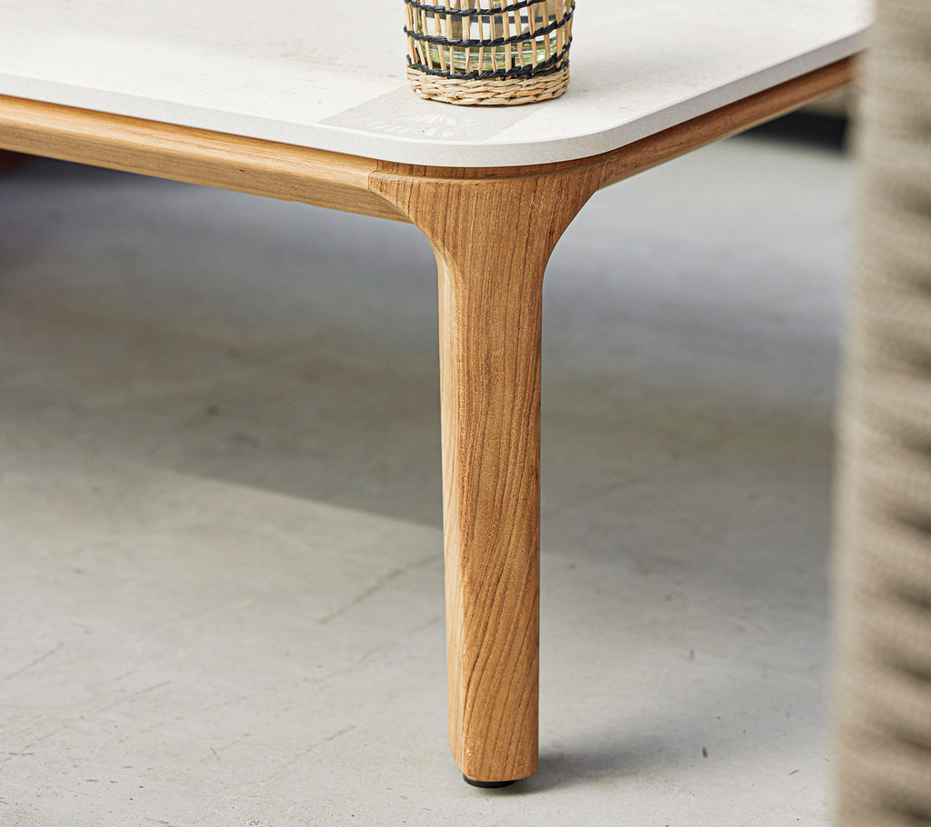 Una mesa elegante con una superficie lisa y una pata de madera natural, rematada con una cesta decorativa tejida.