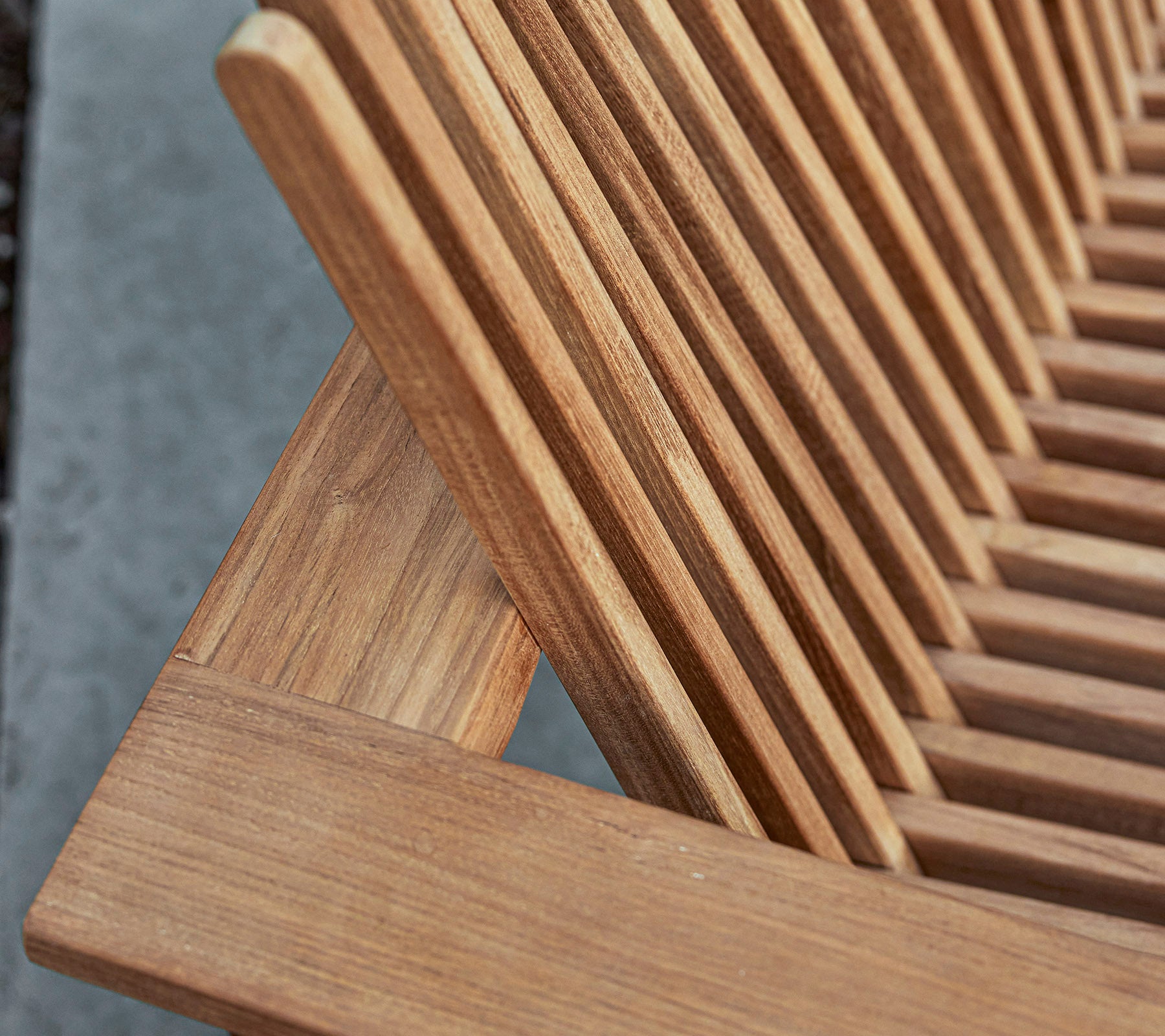 Primer plano de una pieza de mobiliario de madera con un diseño de listones, que muestra la veta natural y los detalles de la artesanía.