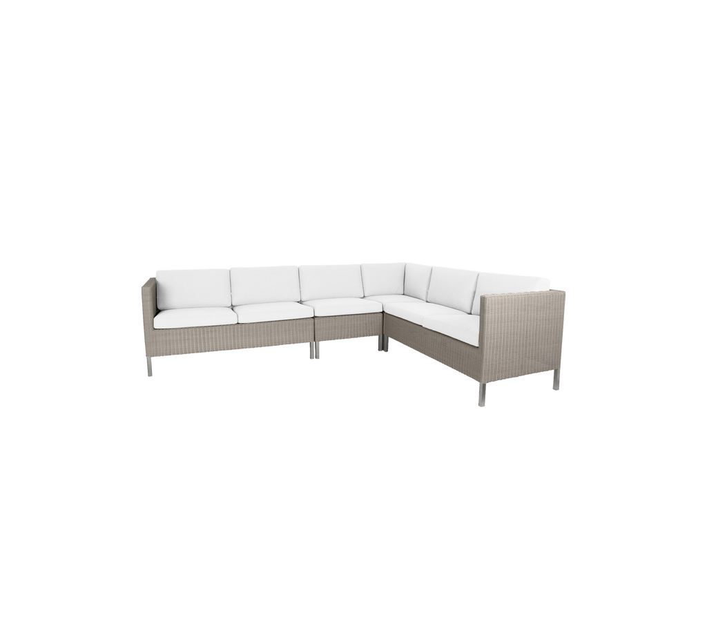 Sofá esquinero exterior elegante con cojines blancos acolchados y un diseño moderno de mimbre, perfecto para reuniones y relajación.