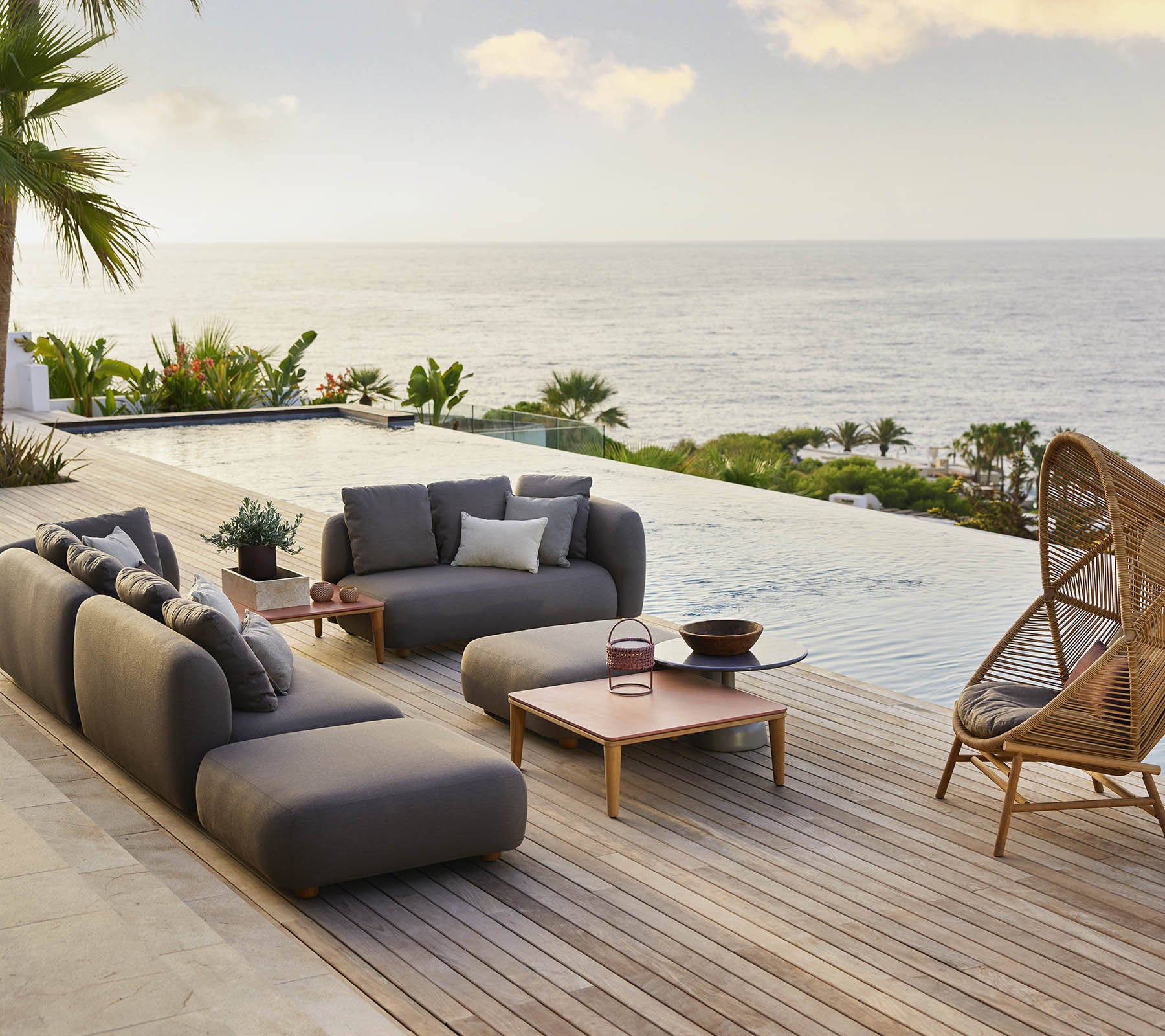Estilo de área de lounge que presenta una acogedora silla colgante en forma de colmena y asientos modernos, complementados con vistas panorámicas del océano y una vegetación exuberante.