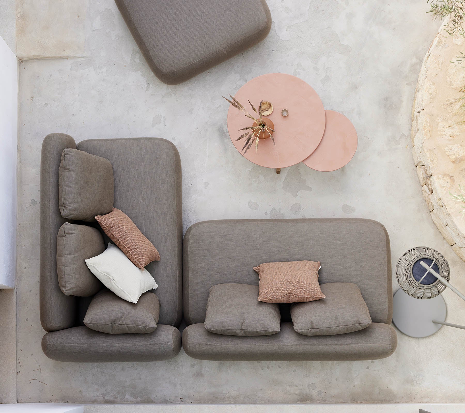 Una disposición de asientos elegante con un sofá de color neutro y cojines decorativos, acompañado de una mesa de café de diseño único.