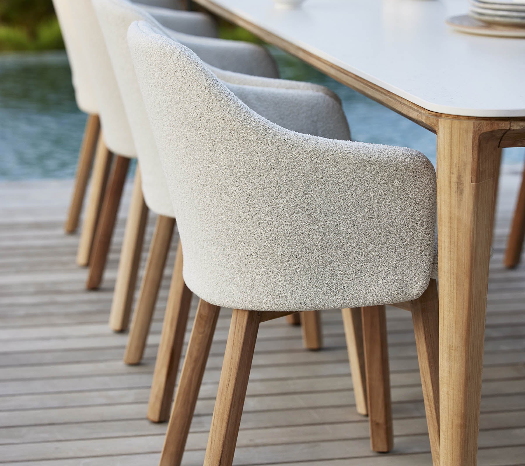 Sillas tapizadas elegantes con patas de madera alineadas junto a una mesa, que ofrecen un aspecto moderno y acogedor para cenas o reuniones.