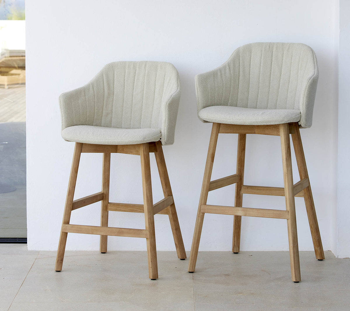 Dos sillas elegantes de color claro con respaldos curvados y patas de madera, que muestran un diseño moderno y cómodo.