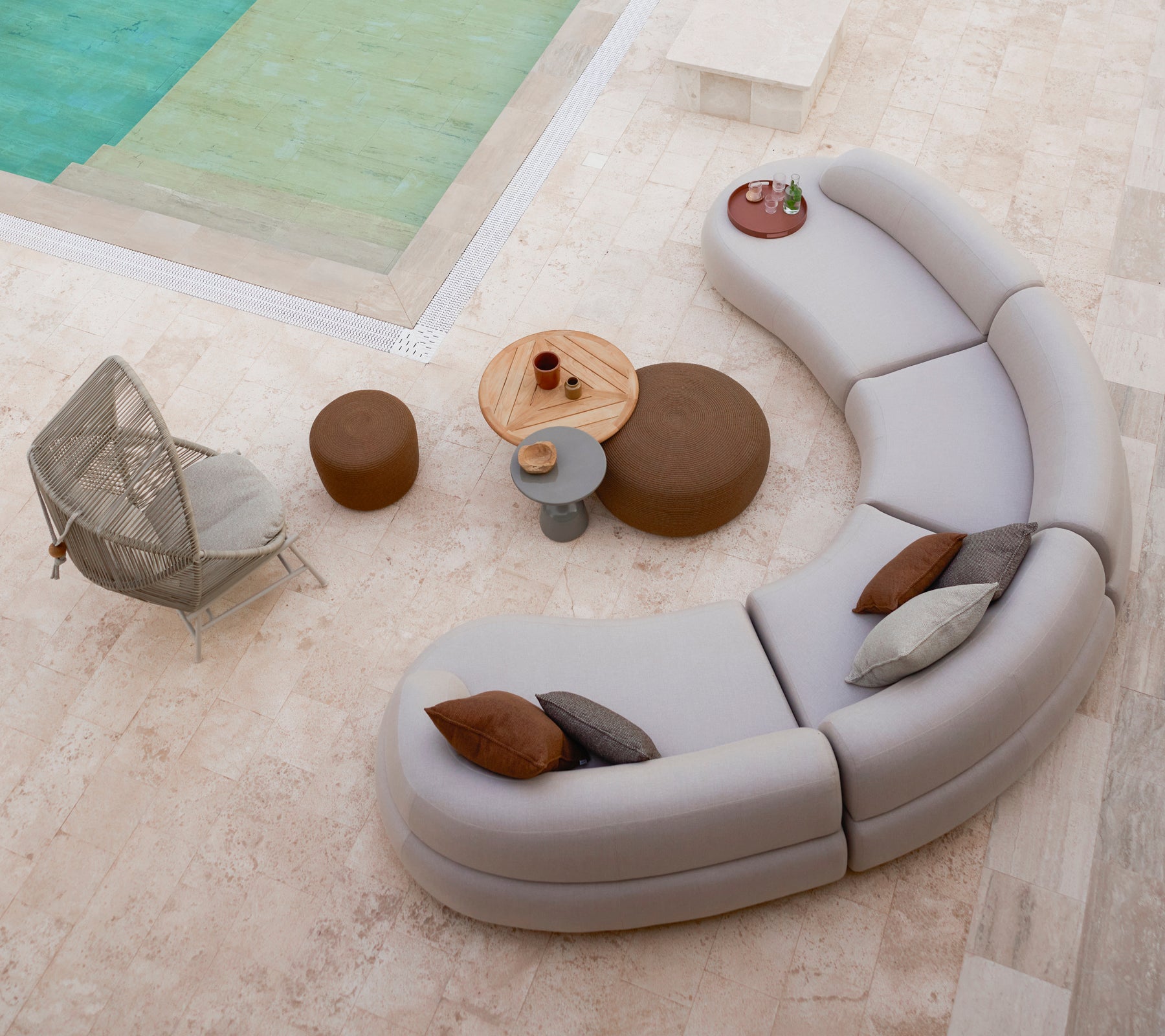 Asientos de salón curvados dispuestos con reposapiés circulares pequeños y grandes, junto a una silla Hive y una mesa redonda en un entorno elegante.