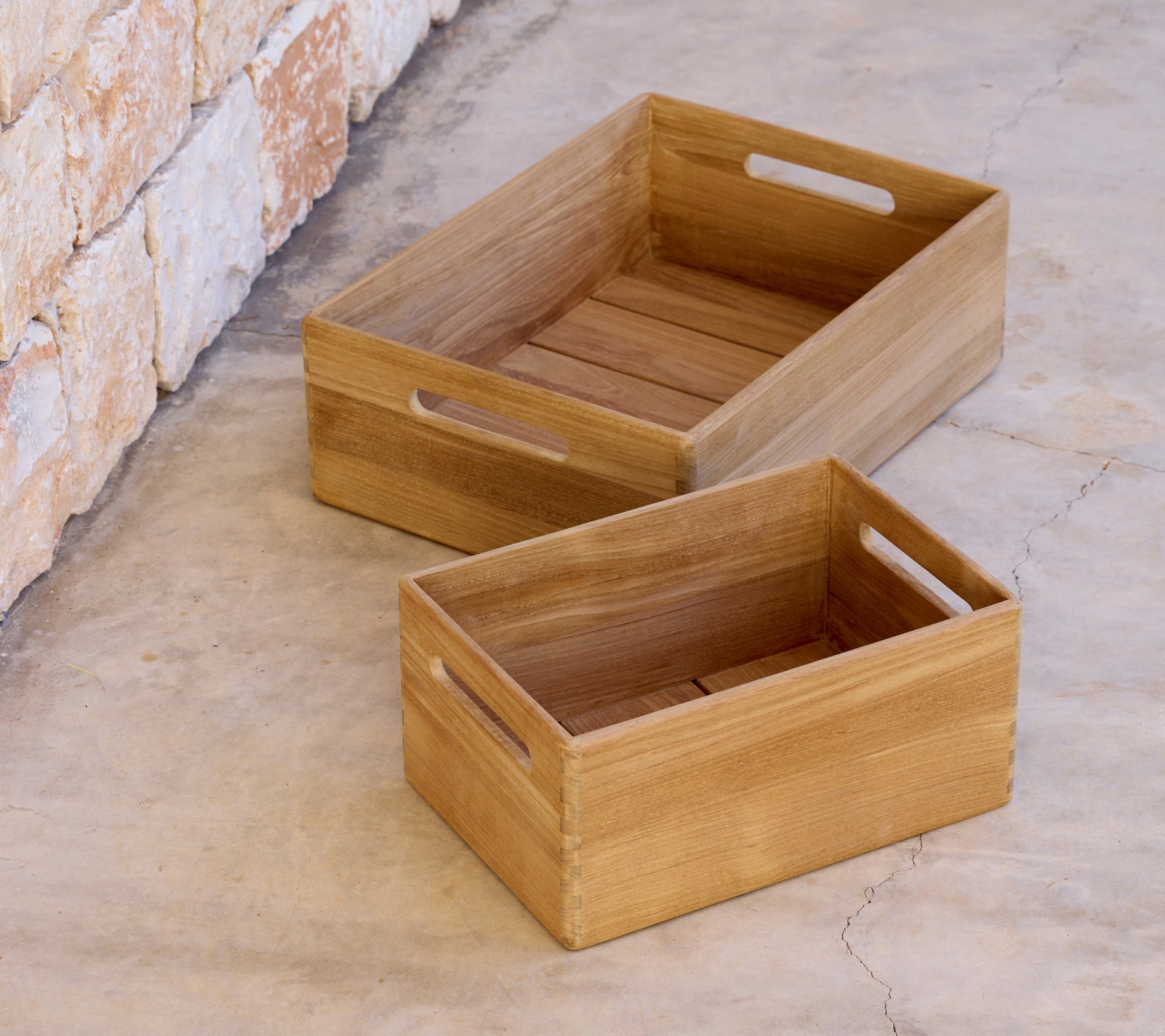 Dos cajas de madera de diferentes tamaños colocadas sobre una superficie de concreto.
