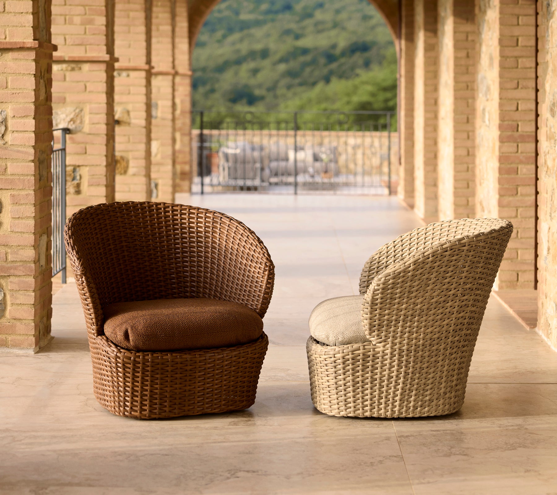 Dos sillas de lounge costeras elegantes en mimbre marrón y crema, con cojines cómodos y un diseño moderno.
