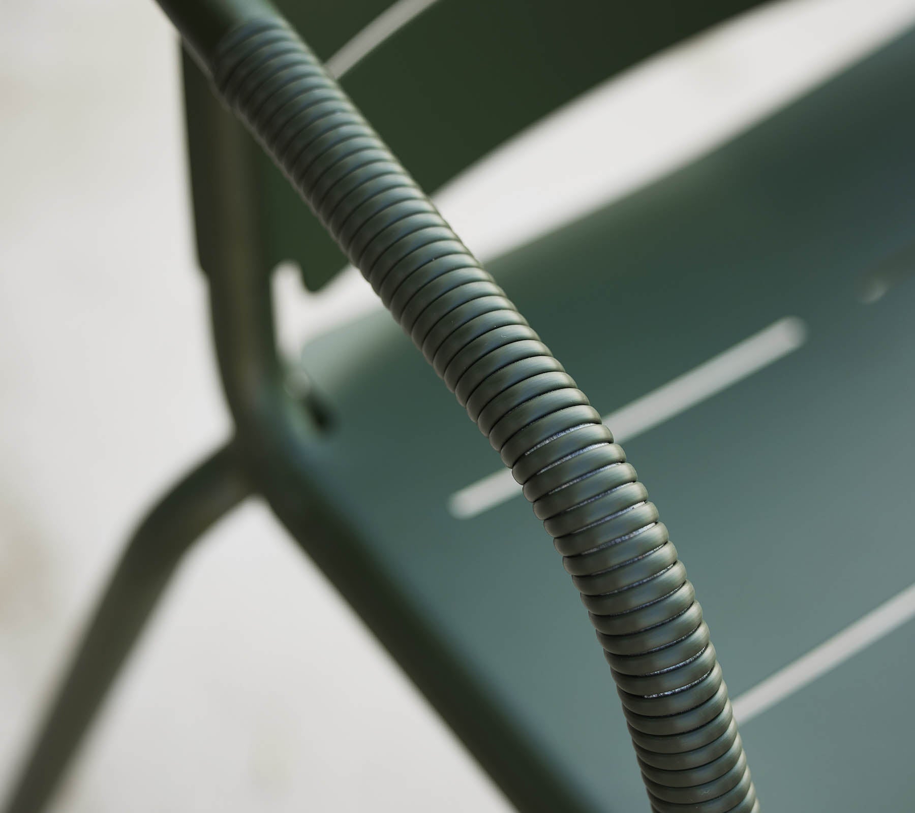 Acercamiento a una silla Copenhagen verde, destacando su reposabrazos curvado y diseño elegante con ranuras sutiles en el asiento.