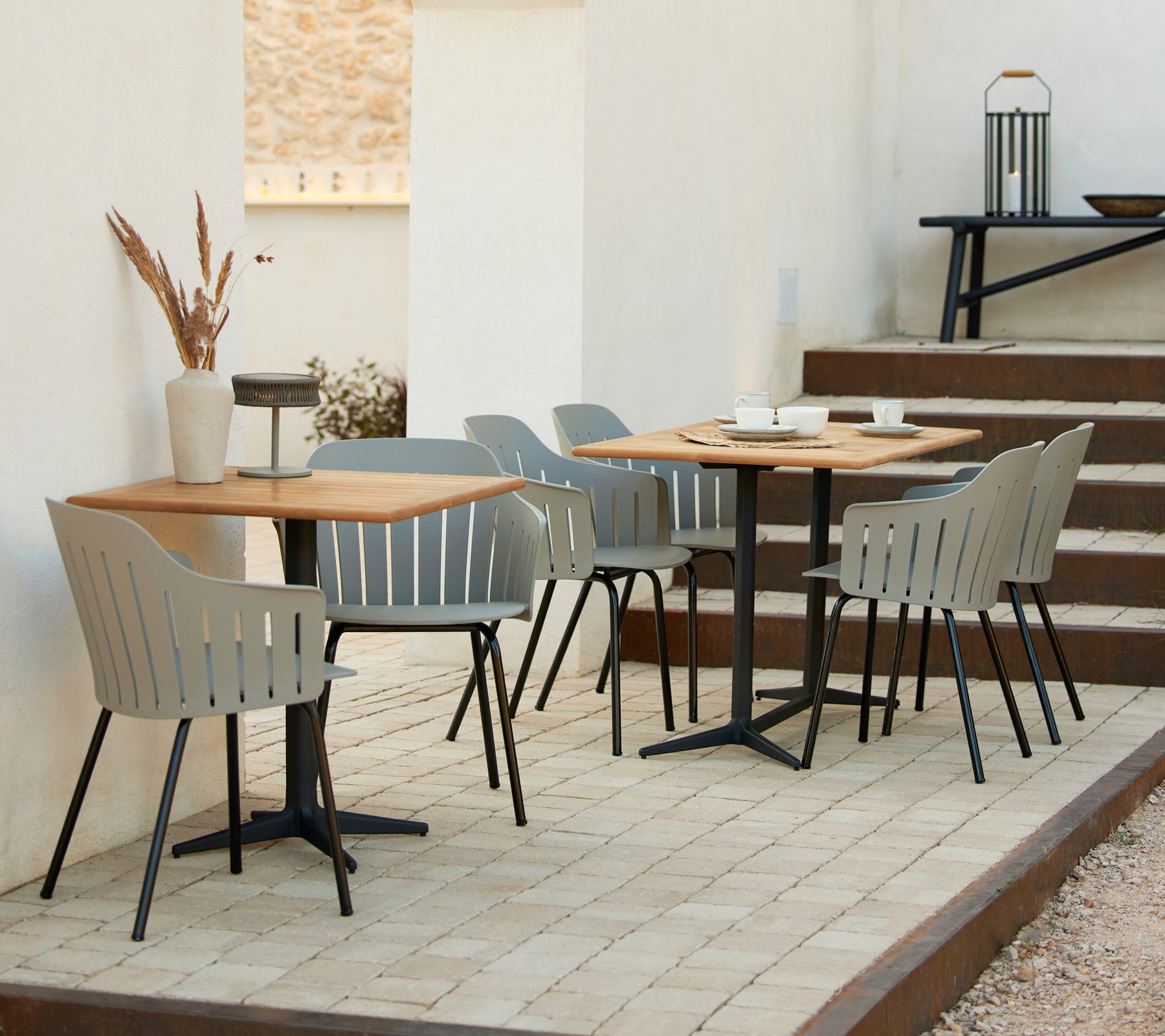 Un entorno de café elegante con mesas de madera, sillas grises y acentos decorativos, ideal para reuniones informales y relajación.