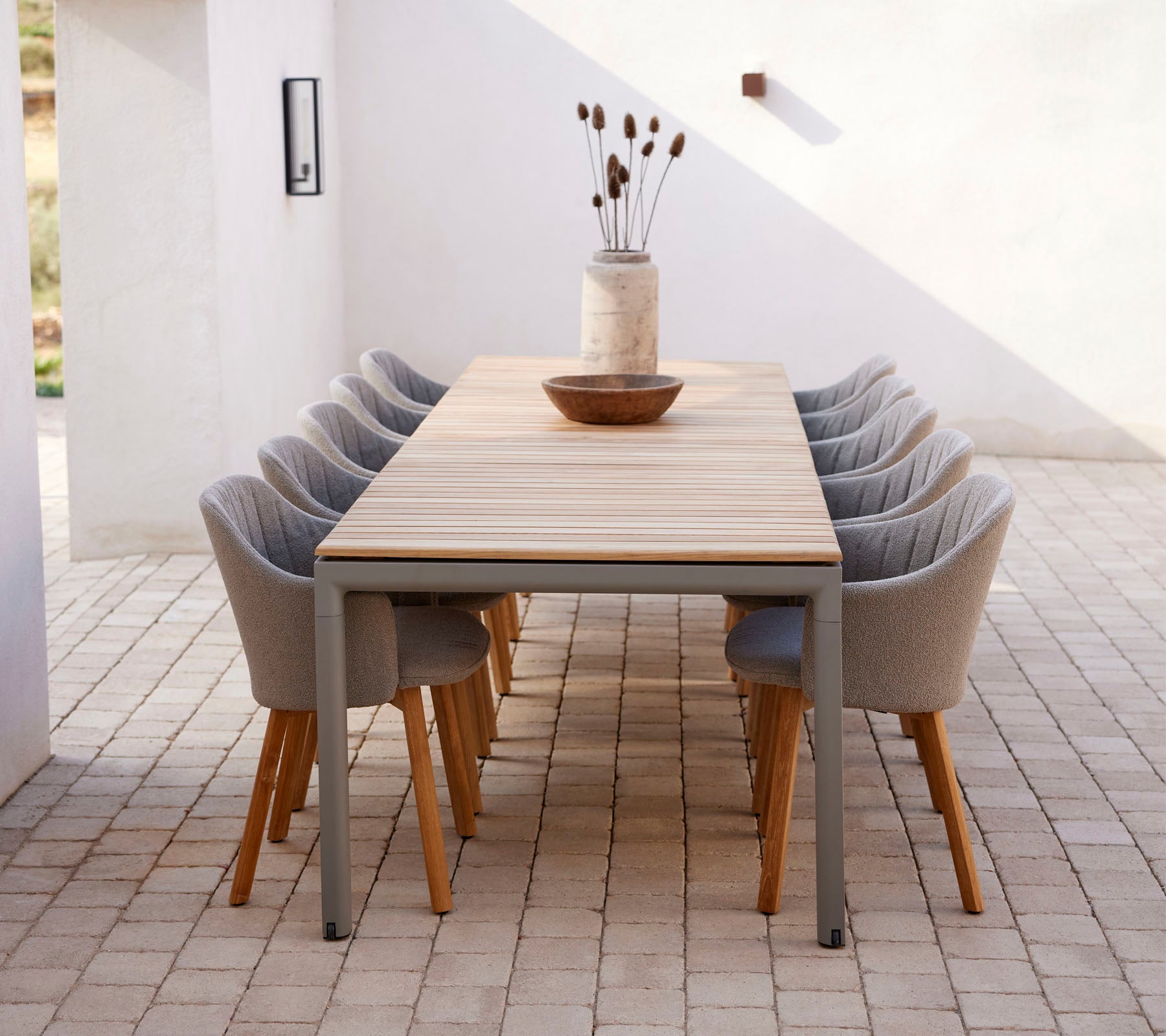 Una larga mesa con sillas modernas, decorada con un jarrón y un cuenco, creando un espacio acogedor para reuniones.