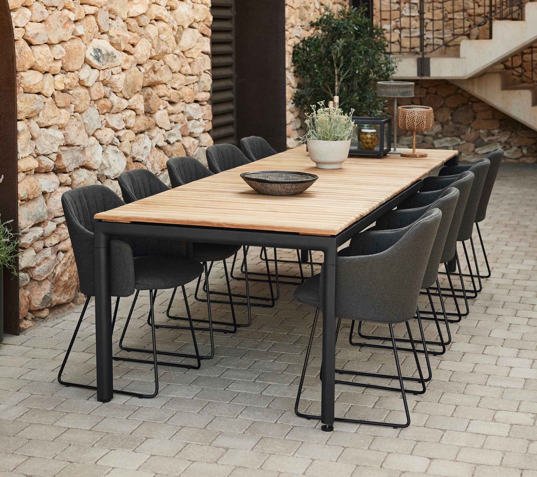 Mesa de comedor elegante con una tapa de madera y patas de metal negro, rodeada de sillas grises, perfecta para reuniones.