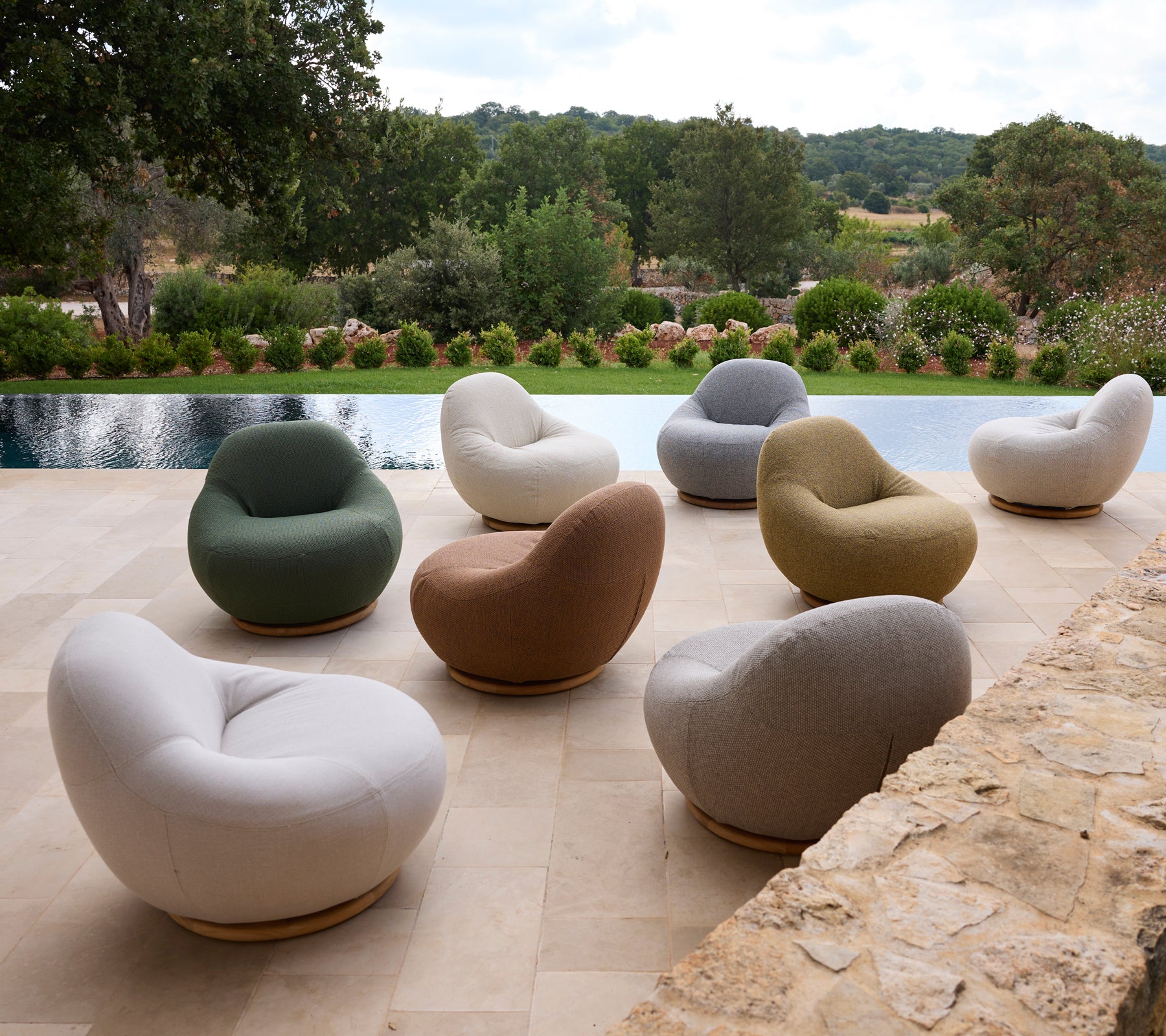 Conjunto de sillas modernas en varios colores dispuestas alrededor de una piscina.