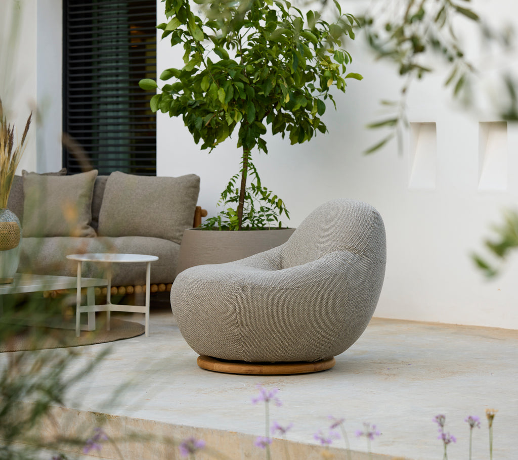 Configuración moderna de salón con una silla gris, un cojín gris y una mesa blanca.