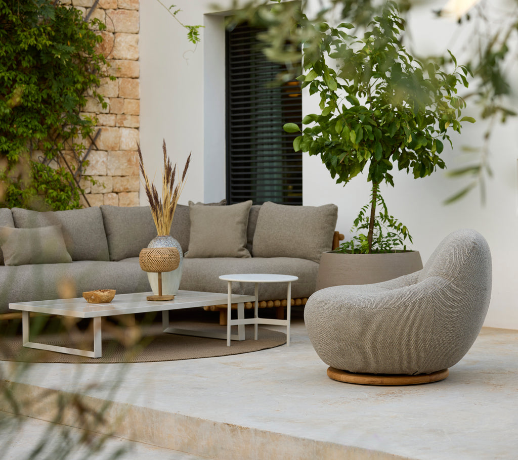 Área de estar moderna con un sofá seccional gris, mesa de café blanca y una silla redonda.