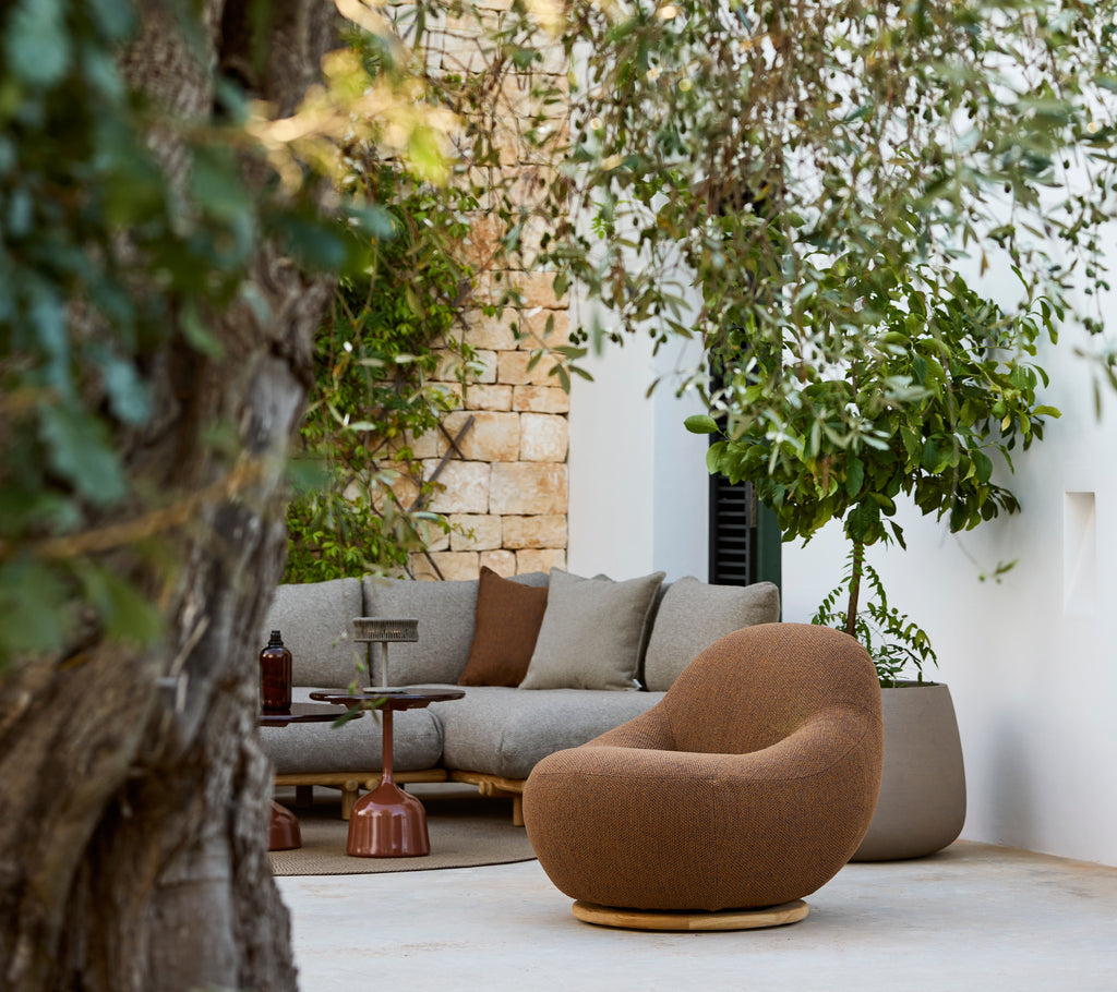 Zona de salón moderna con una silla marrón y un sofá gris.
