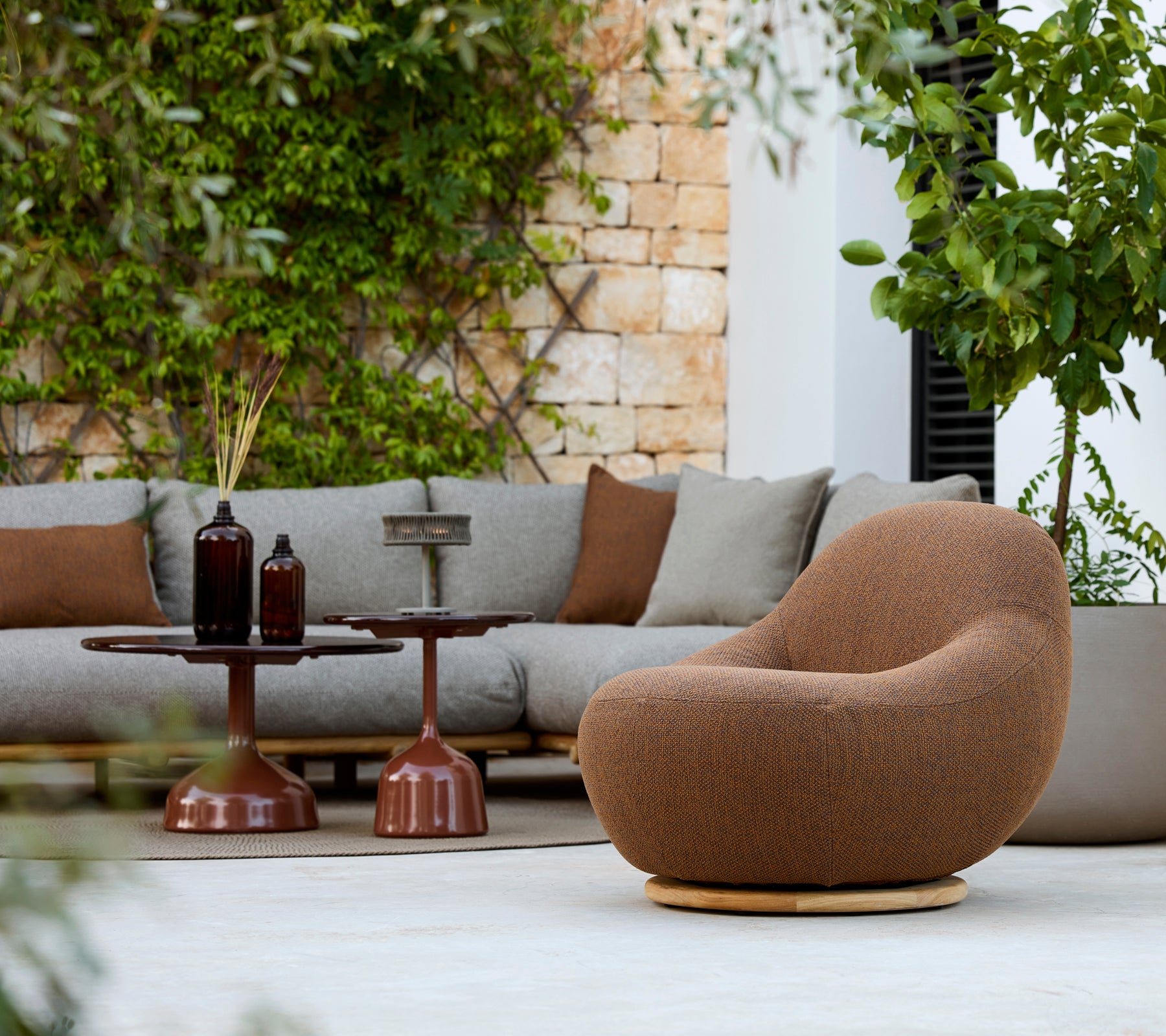 Zona de estar moderna con un sillón marrón, un sofá gris y una mesa auxiliar marrón.