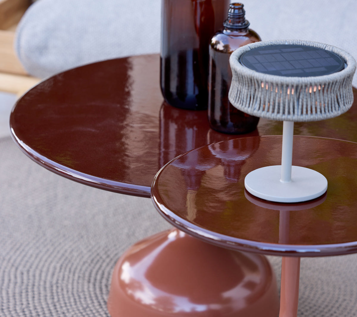 Mesa marrón moderna con una lámpara blanca y botellas sobre una superficie texturizada.