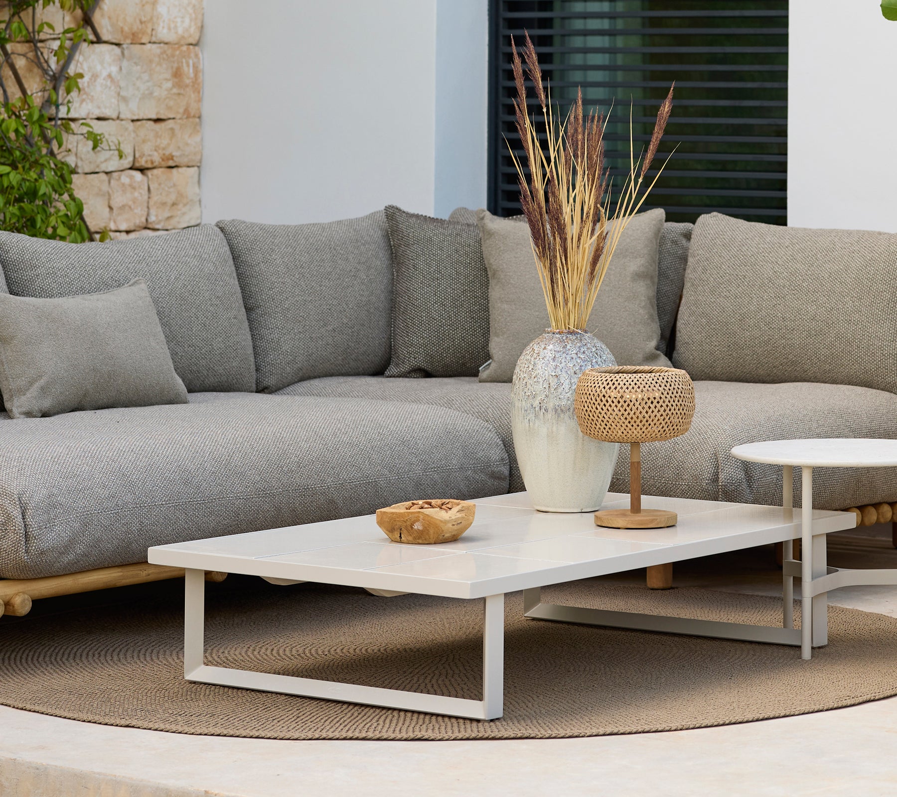 Área de estar moderna con un sofá gris y una mesa de café blanca con decoración.