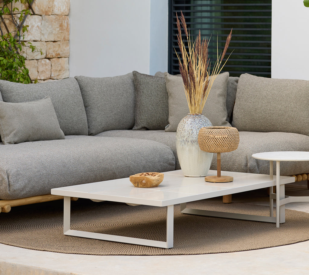 Área de estar moderna con un sofá gris y una mesa de café blanca con decoración.