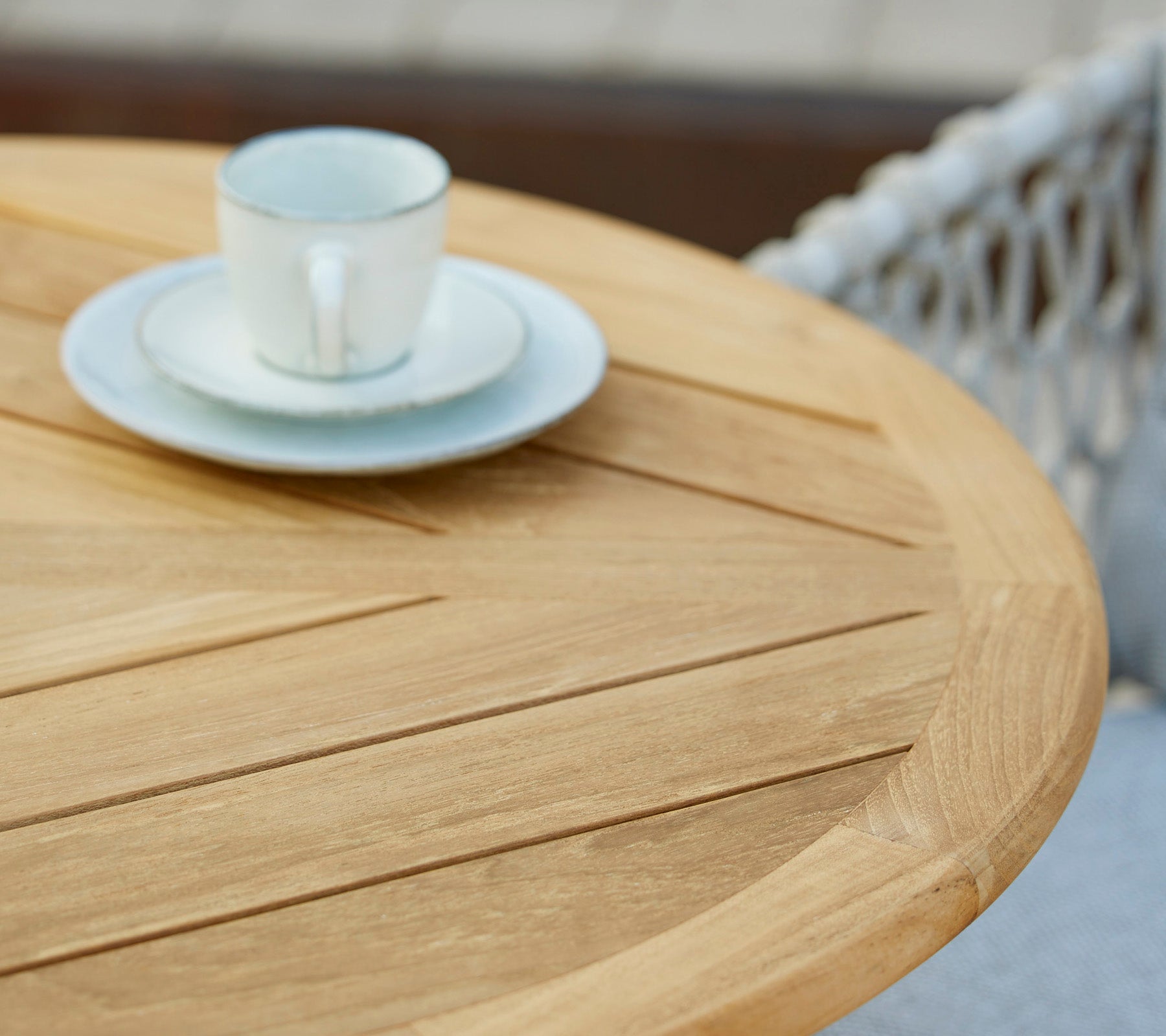 Una mesa de madera con una taza de café y un plato encima, mostrando un ambiente de café minimalista y acogedor.