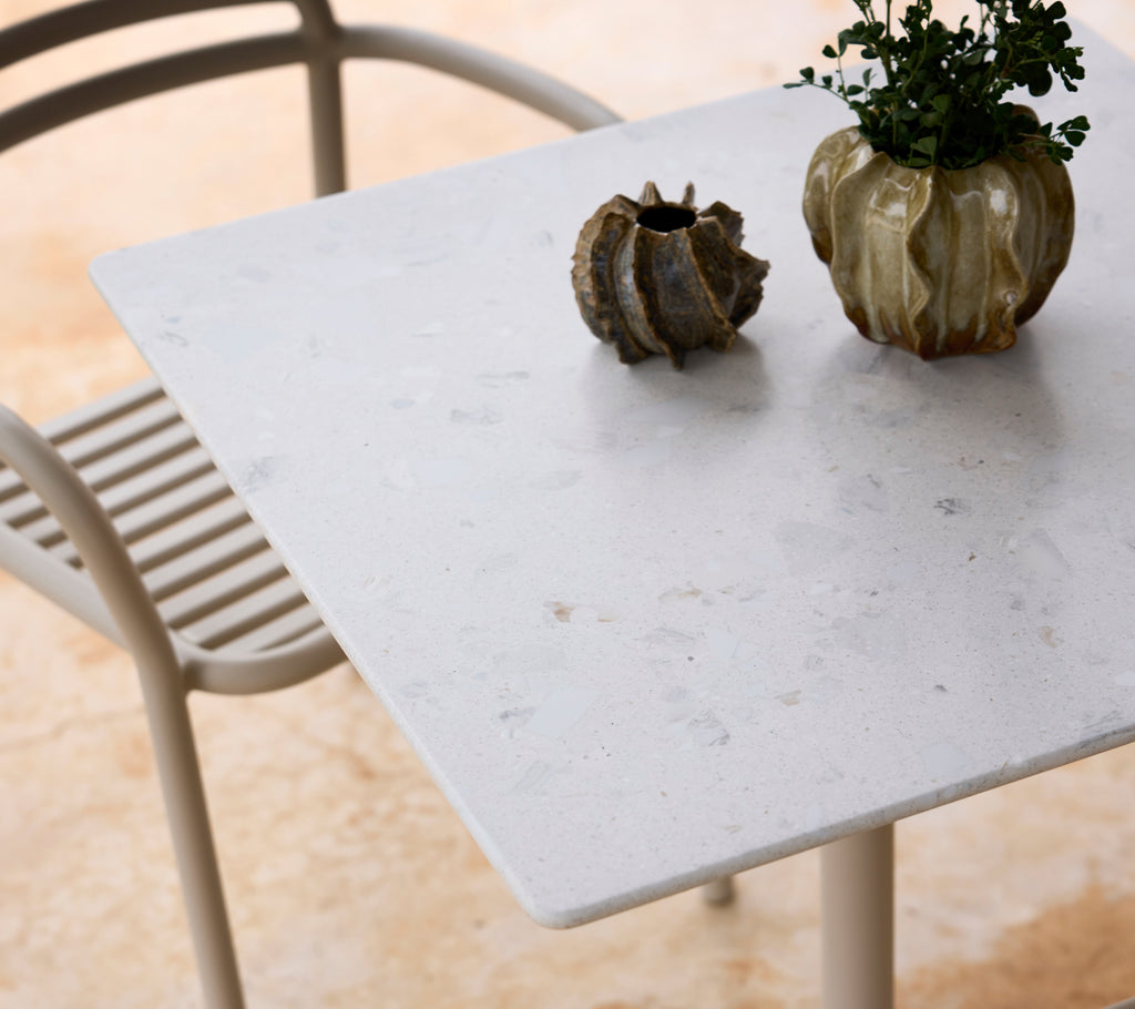 Mesa blanca con una silla gris y un centro de planta verde.