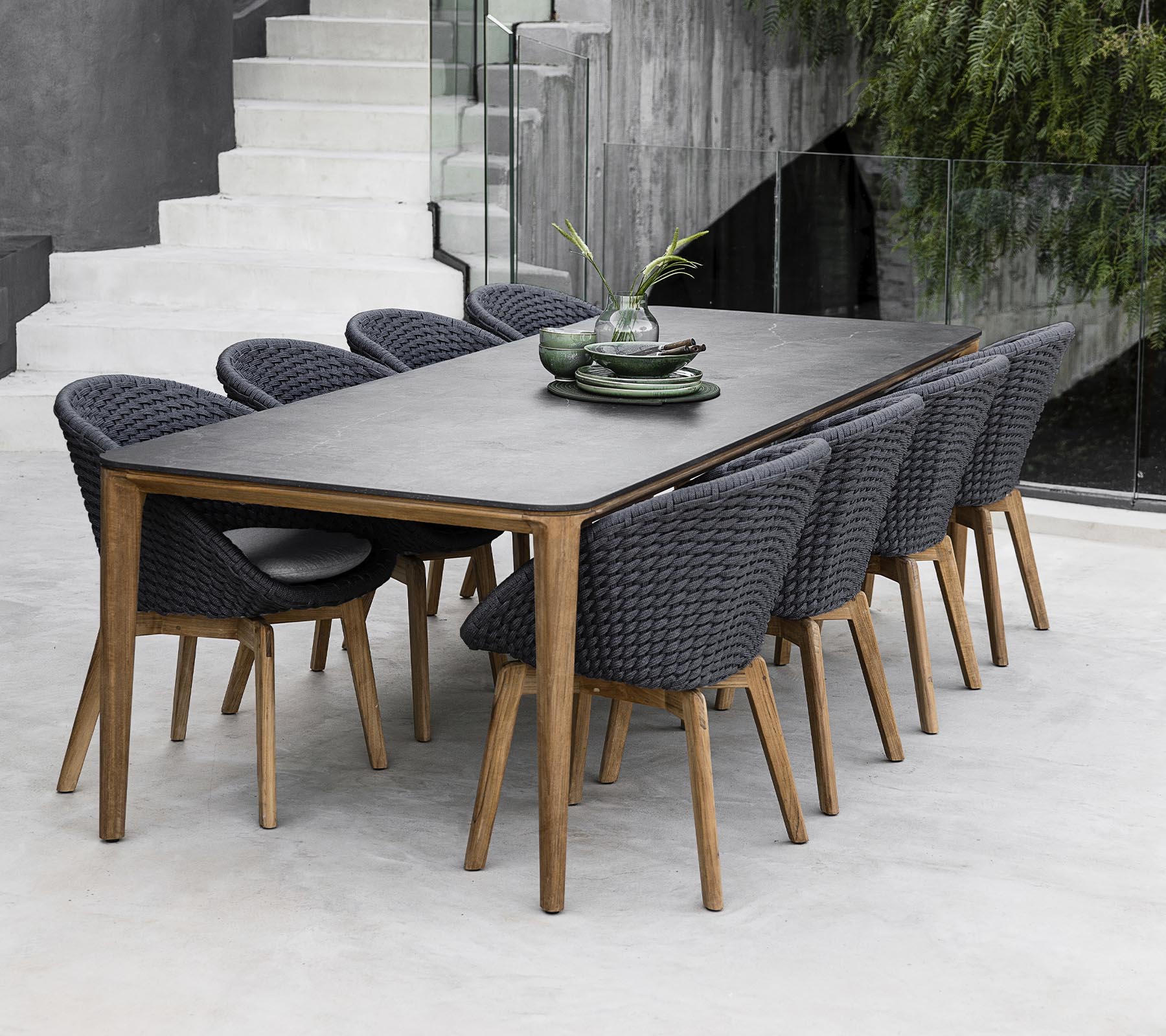 Una mesa moderna rodeada de ocho sillas elegantes, adornada con plantas decorativas en la mesa en un entorno elegante y minimalista.