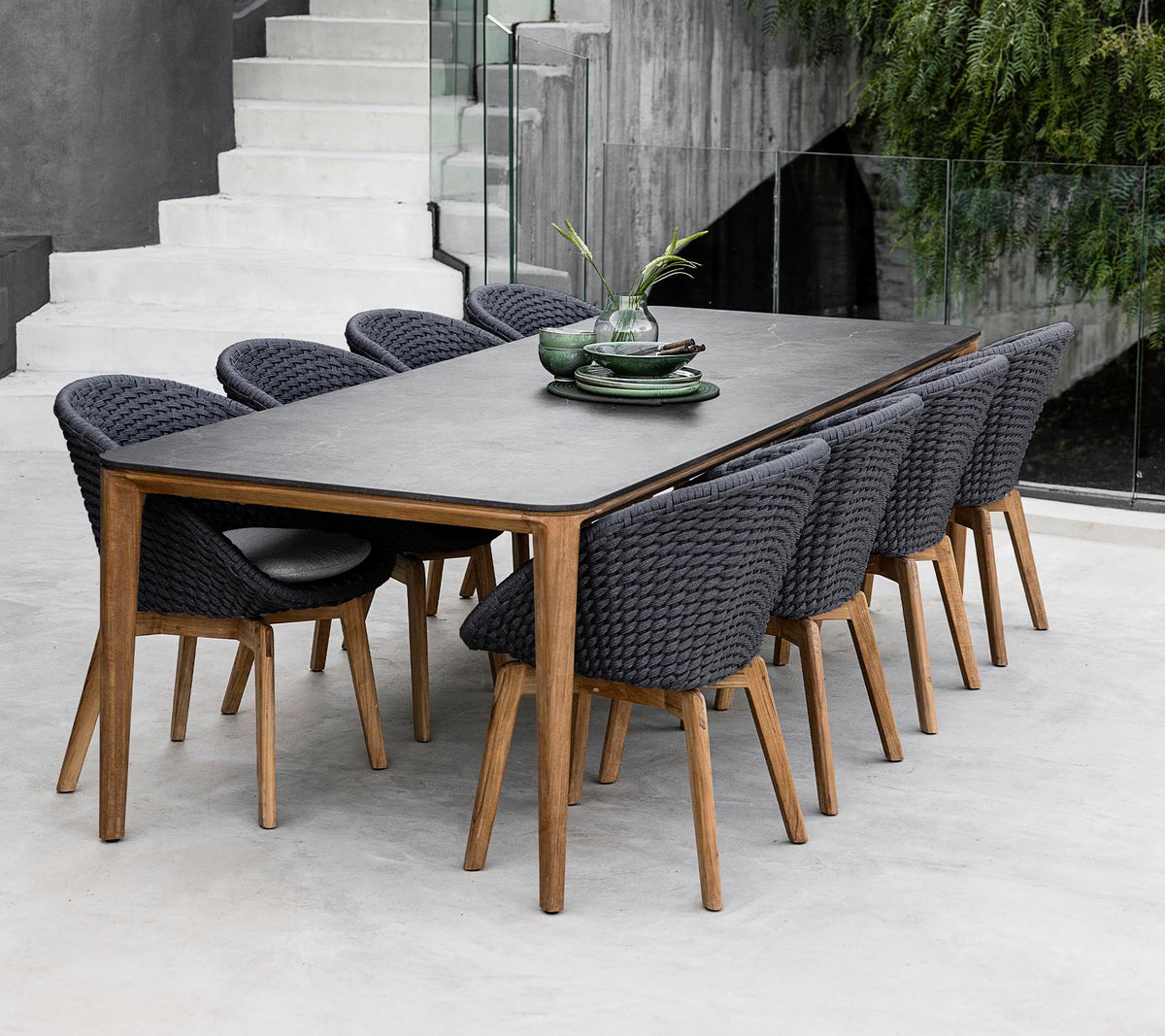 Una mesa moderna rodeada de ocho sillas elegantes, adornada con plantas decorativas en la mesa en un entorno elegante y minimalista.
