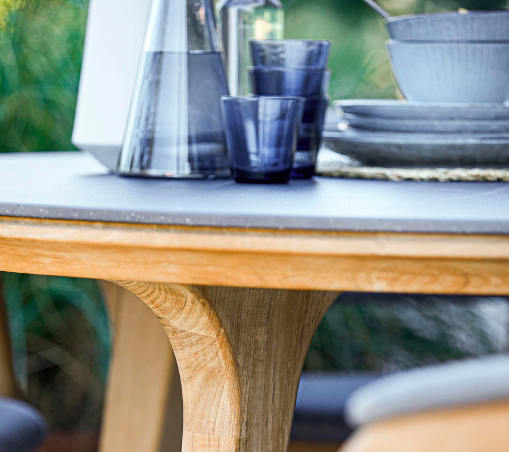 Una mesa redonda de madera con una superficie lisa, acompañada de cristalería y platos de cerámica, creando una disposición de comedor elegante.