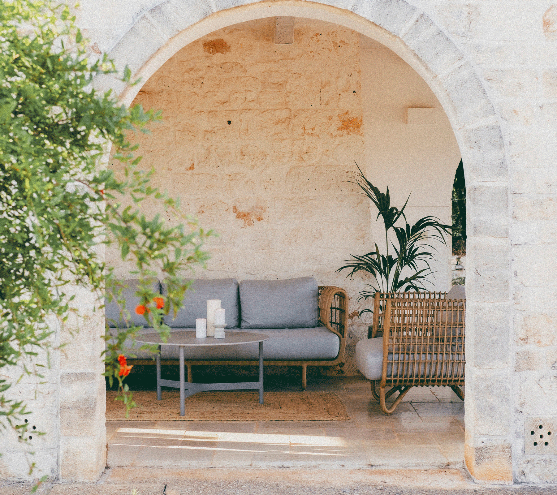 Área de asientos acogedora enmarcada por un arco, con un sofá, una mesa de café, plantas y elementos decorativos.