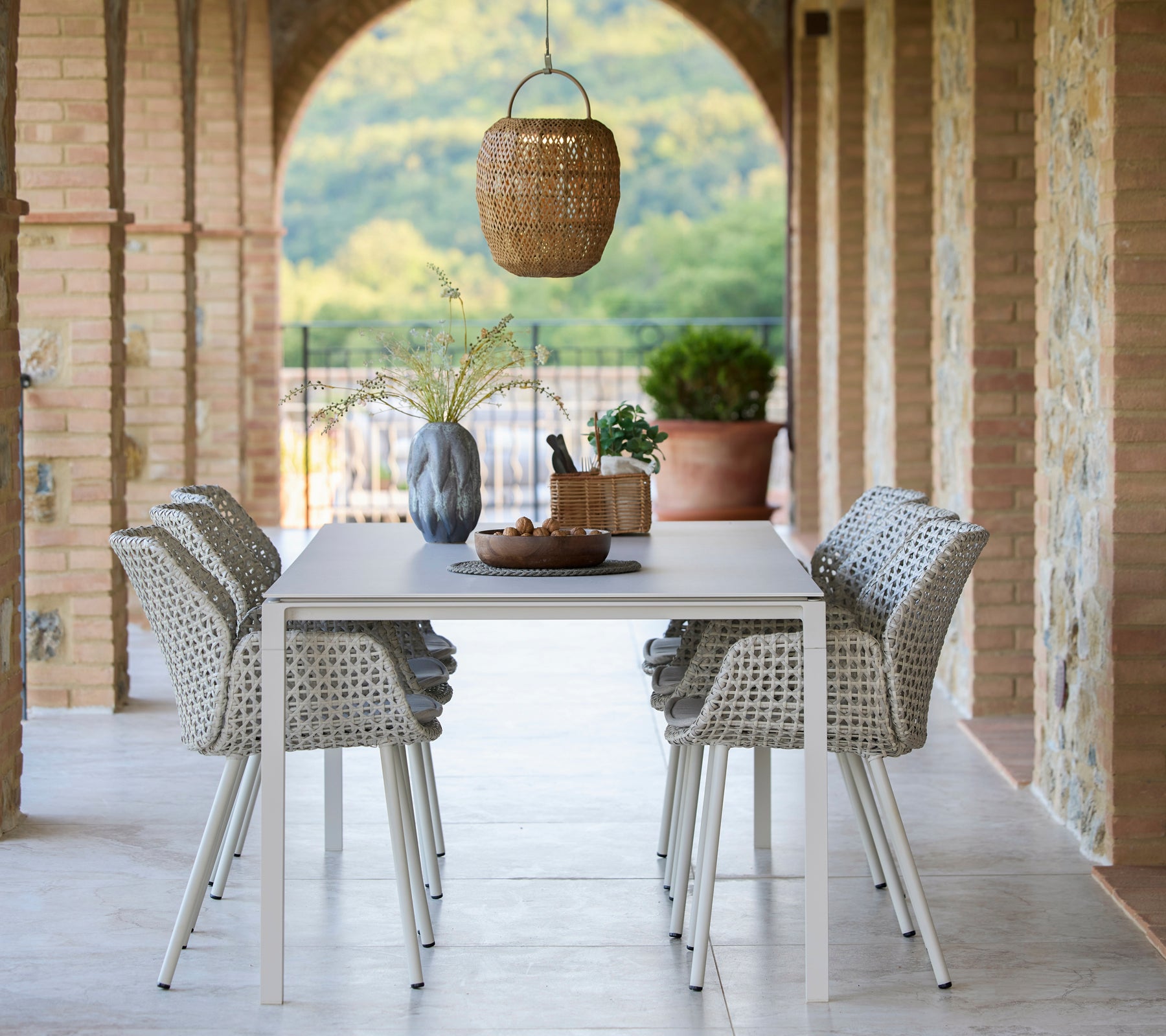 Un espacio de comedor con una mesa Pure rodeada de sillas de comedor Vibe, realzado con una lámpara colgante Illusion Glow y elementos decorativos.