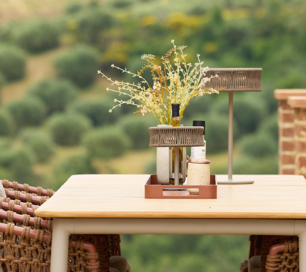 Una mesa de comedor elegante con una lámpara de ilusión y un jarrón de flores, creando un elegante centro de mesa en un entorno sereno.