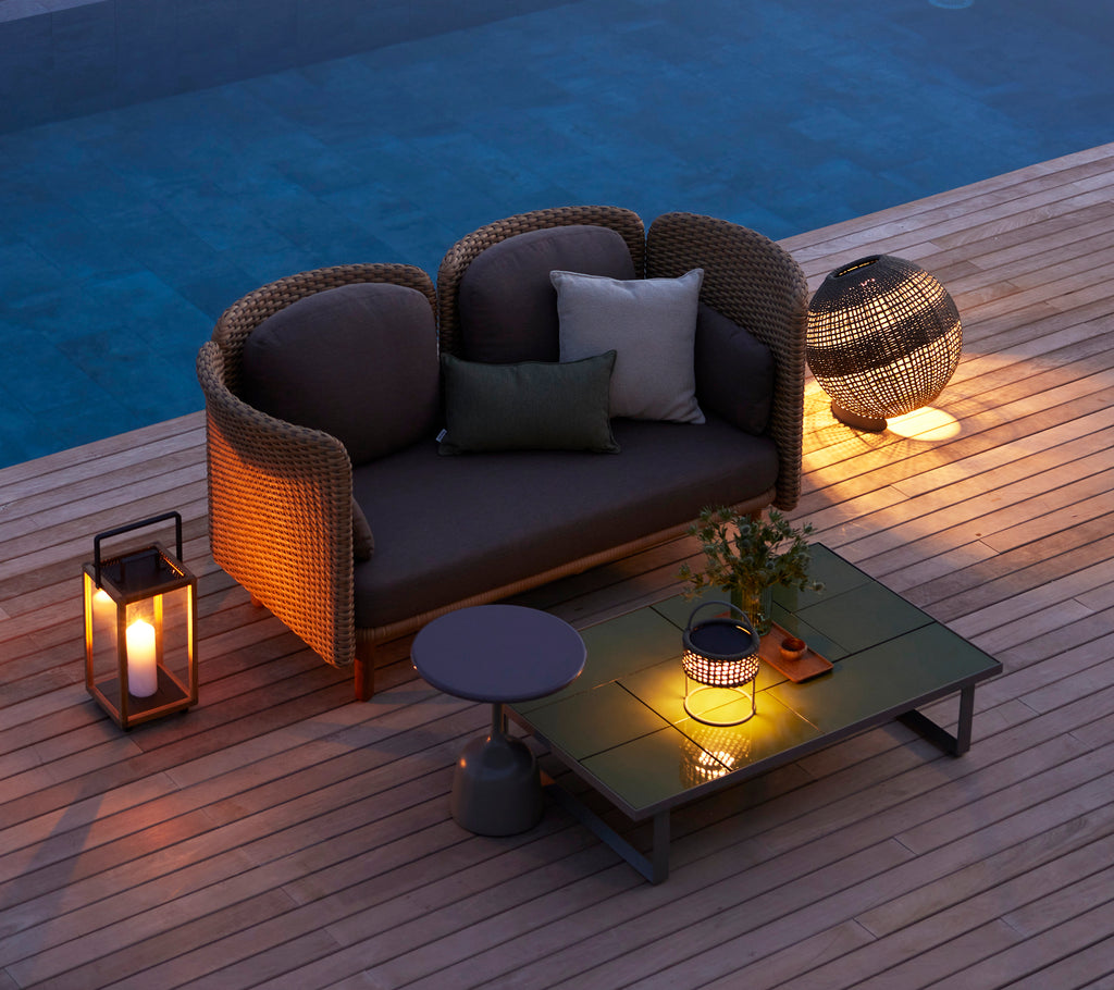 Área de estar acogedora con una lámpara de ilusión redonda, una mesa de café de vidrio y elementos decorativos, creando un ambiente cálido.