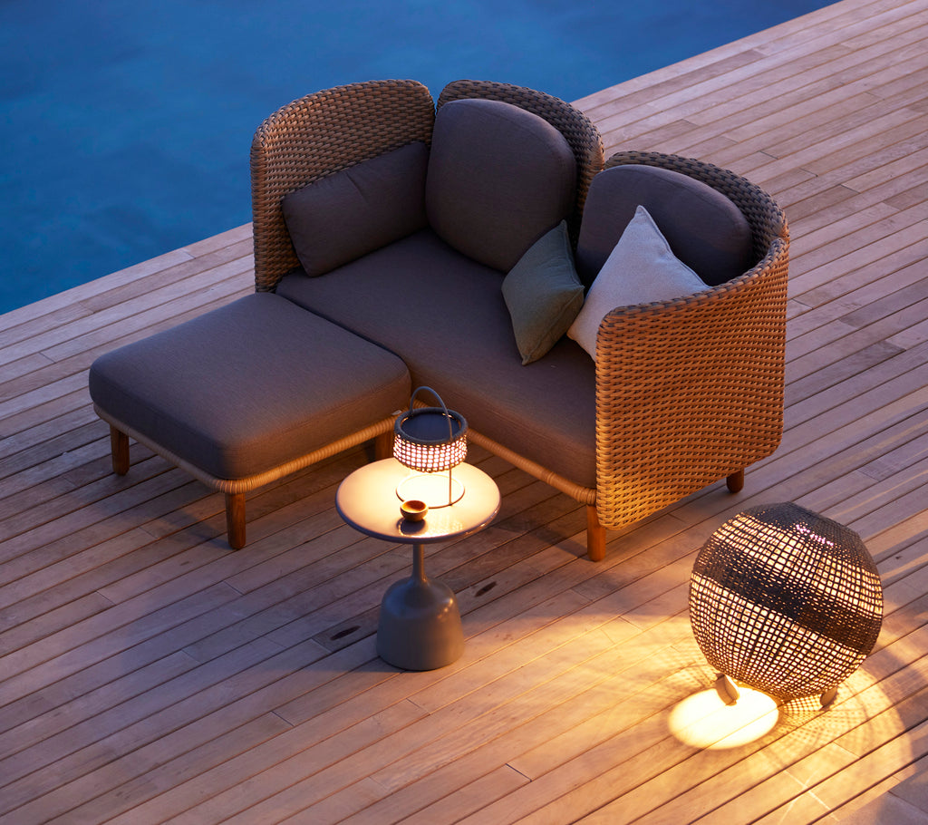 Área de descanso acogedora con una lámpara de ilusión elegante sobre una mesa lateral redonda y muebles de acento modernos, iluminada cálidamente con una luz suave.