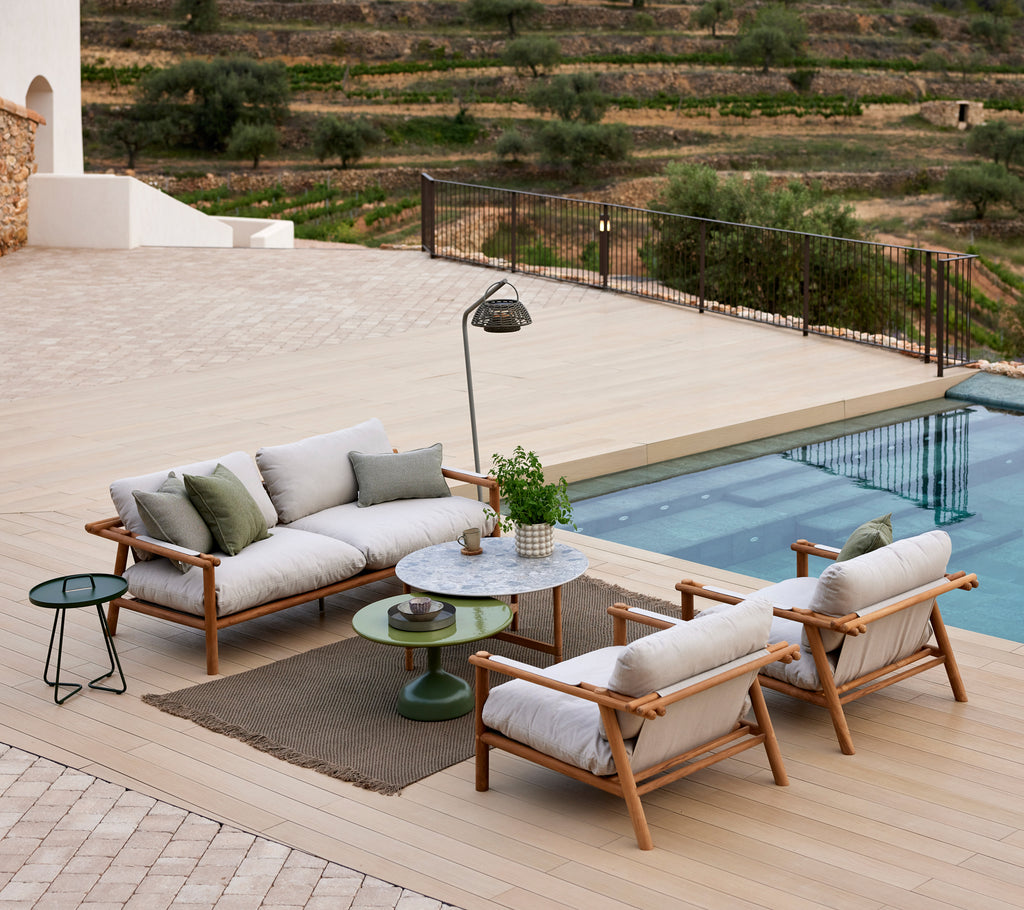 Área de salón acogedora con una alfombra de punto, asientos elegantes, una mesa pequeña y una lámpara de pie cerca de una piscina con vistas escénicas.
