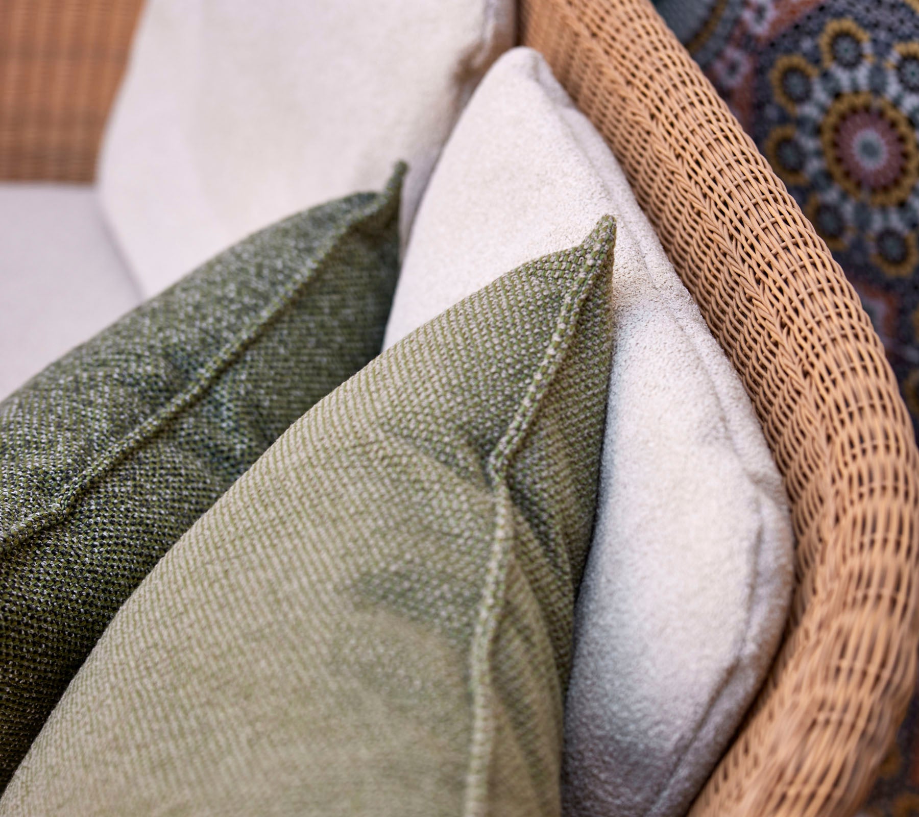 Una vista en primer plano de cojines decorativos en varias texturas y colores, dispuestos sobre una superficie de asiento tejida.