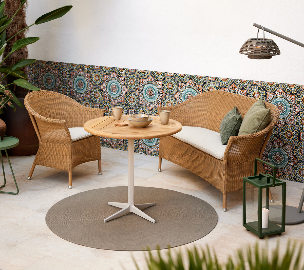 Una acogedora área de estar con sillas de mimbre y una mesa redonda, complementada con vibrantes patrones circulares de fondo.
