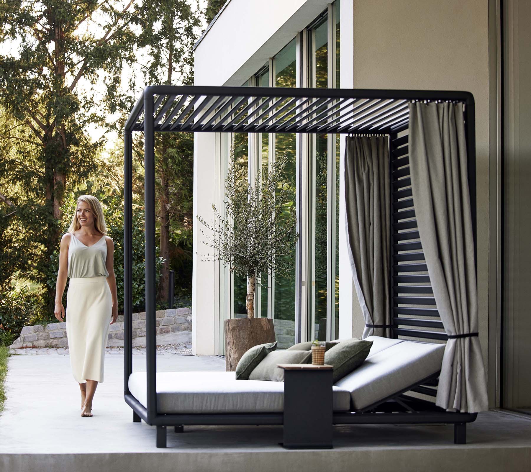 Una cabaña estilosa con un diseño elegante, almohadas suaves, cortinas y una pequeña mesa auxiliar, situada en un entorno natural sereno.