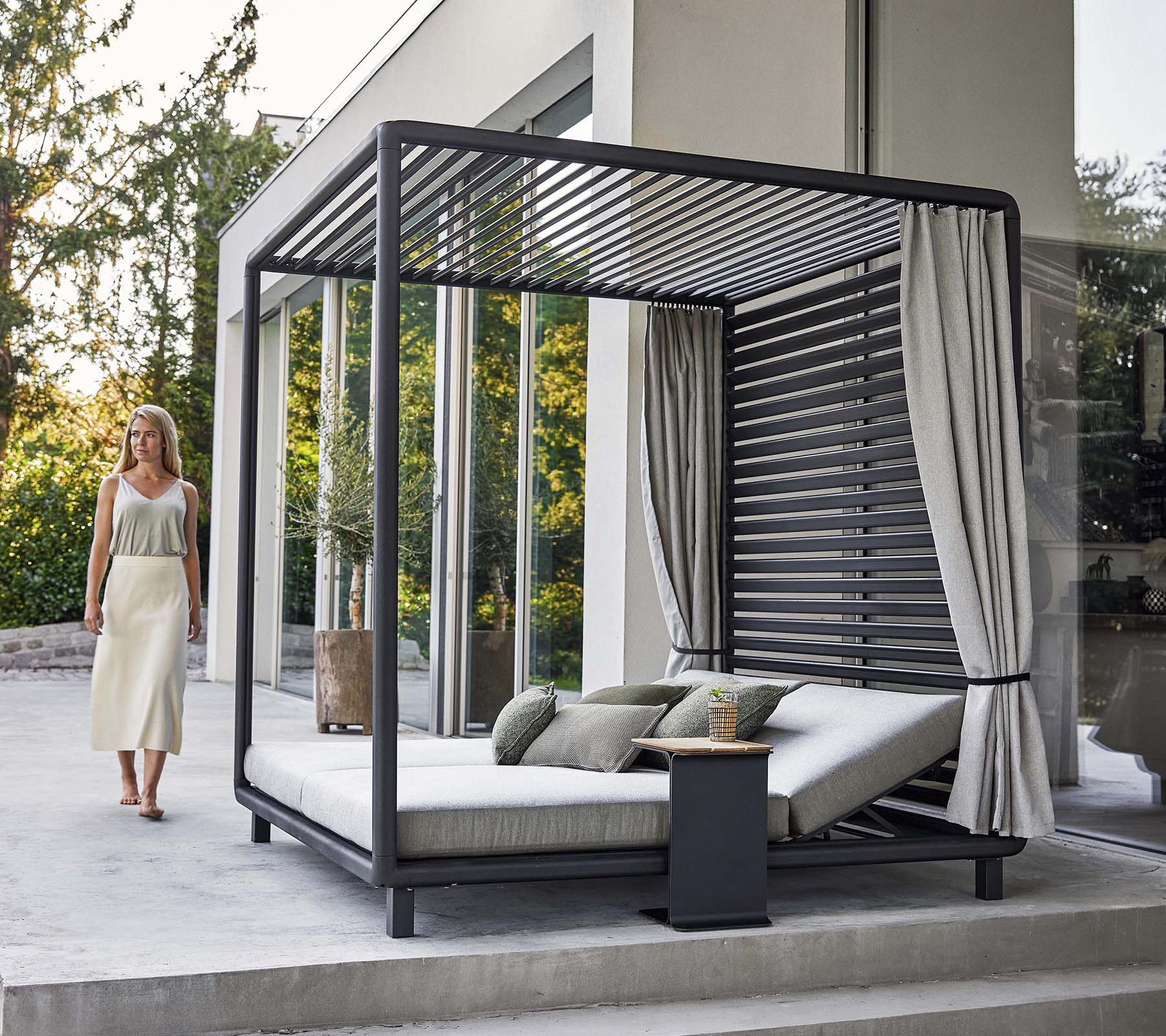 Una cabaña elegante con un diseño moderno, que cuenta con un área de descanso cómoda y cortinas suaves, situada en un entorno sereno.